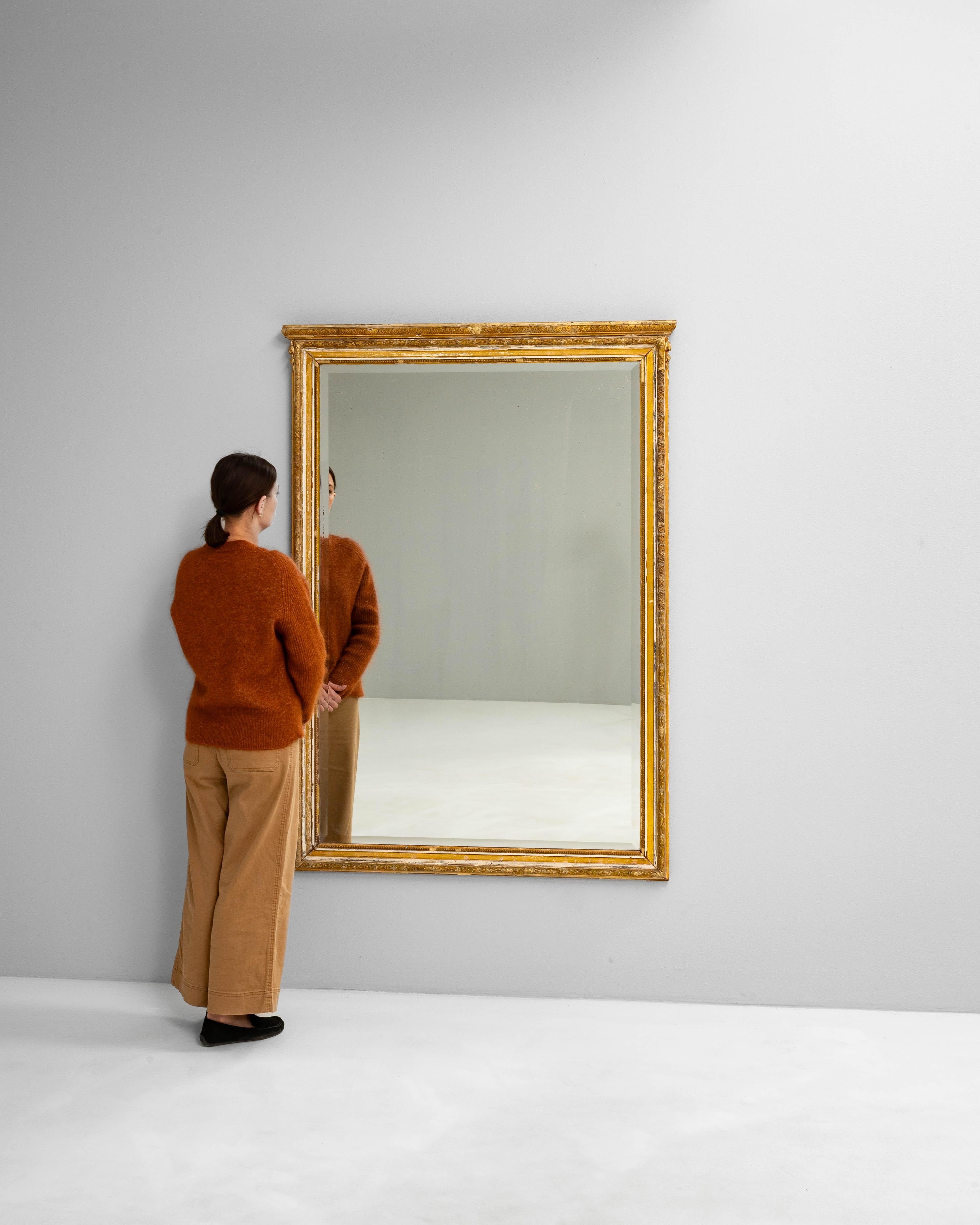Ce miroir français du XIXe siècle est un exemple raffiné du design néoclassique. Il est fabriqué en bois sculpté et recouvert d'une couche de gesso doré à la patine douce et usée par le temps. Le cadre présente un ensemble élégant de motifs