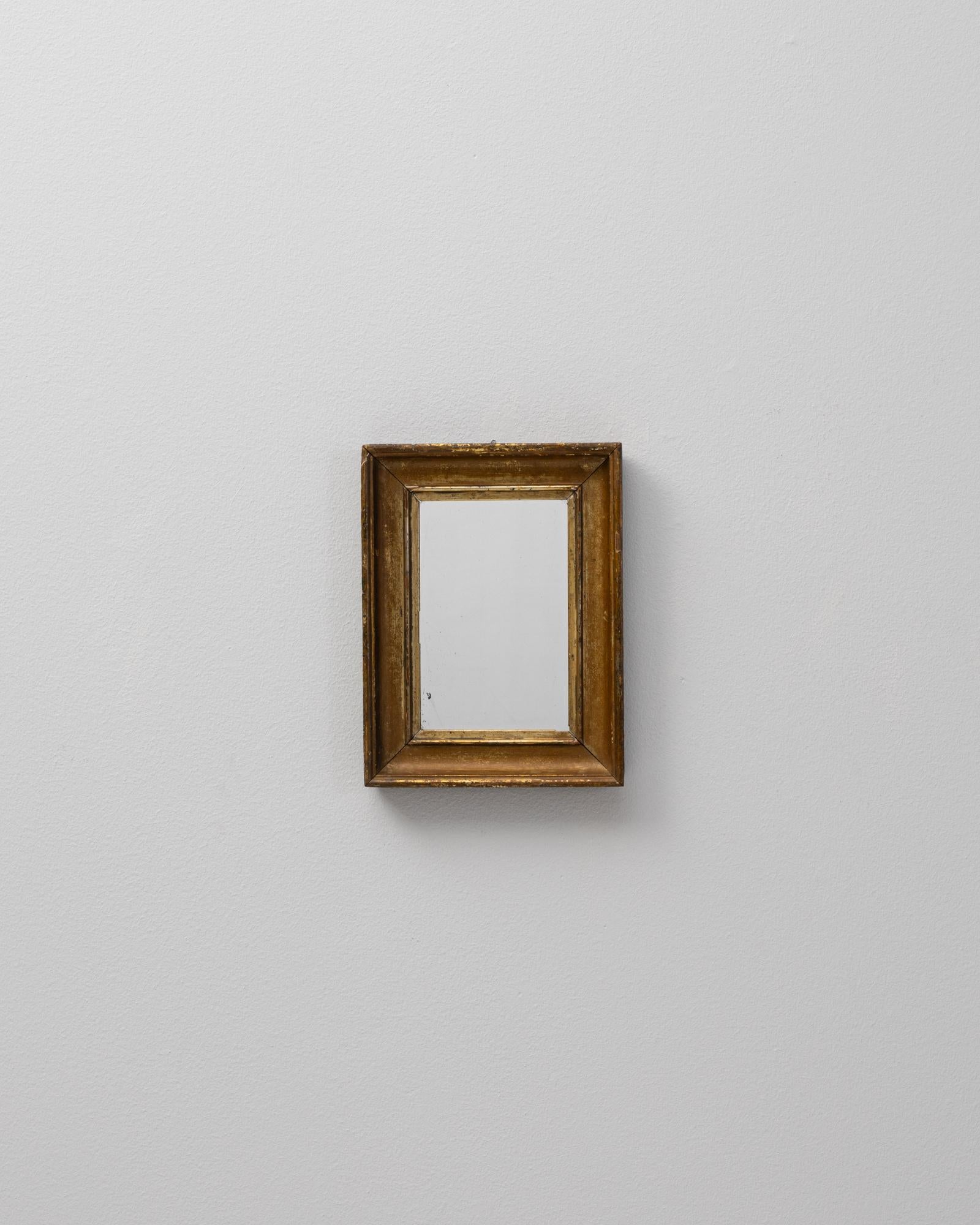 This 19th Century French mirror features a minimalist gilded wooden frame that speaks to refined elegance and timeless simplicity. The frame's subtle profile is gently beveled, with a warm gold finish that has aged beautifully, revealing areas of
