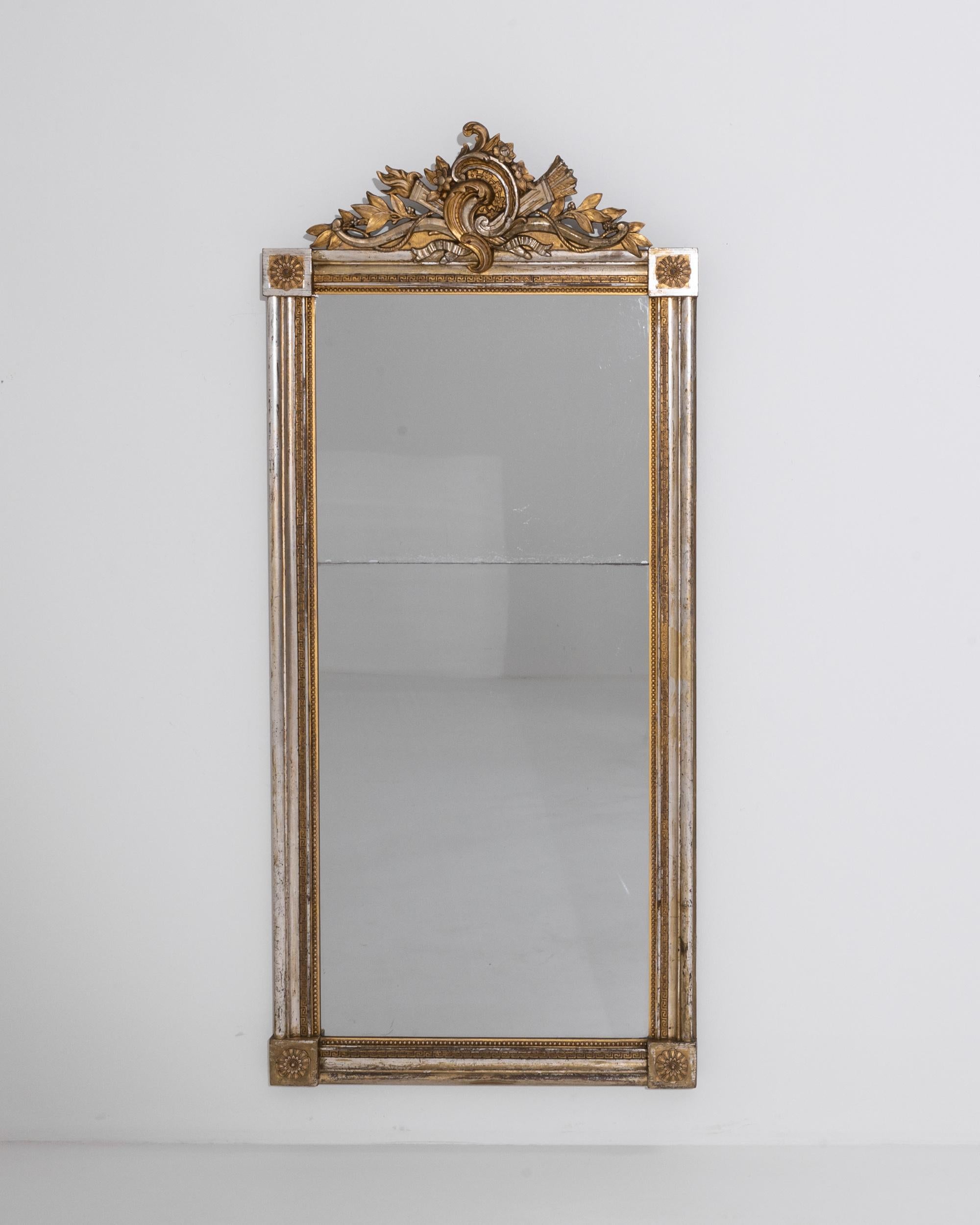 A 19th century gilded wooden mirror produced in France, this ornate piece exudes a sensual baroque inflection. Decorated with fretwork friezes and daintily carved pearl strings, the frame offers an opulent contrast of gilded and silver finishes.