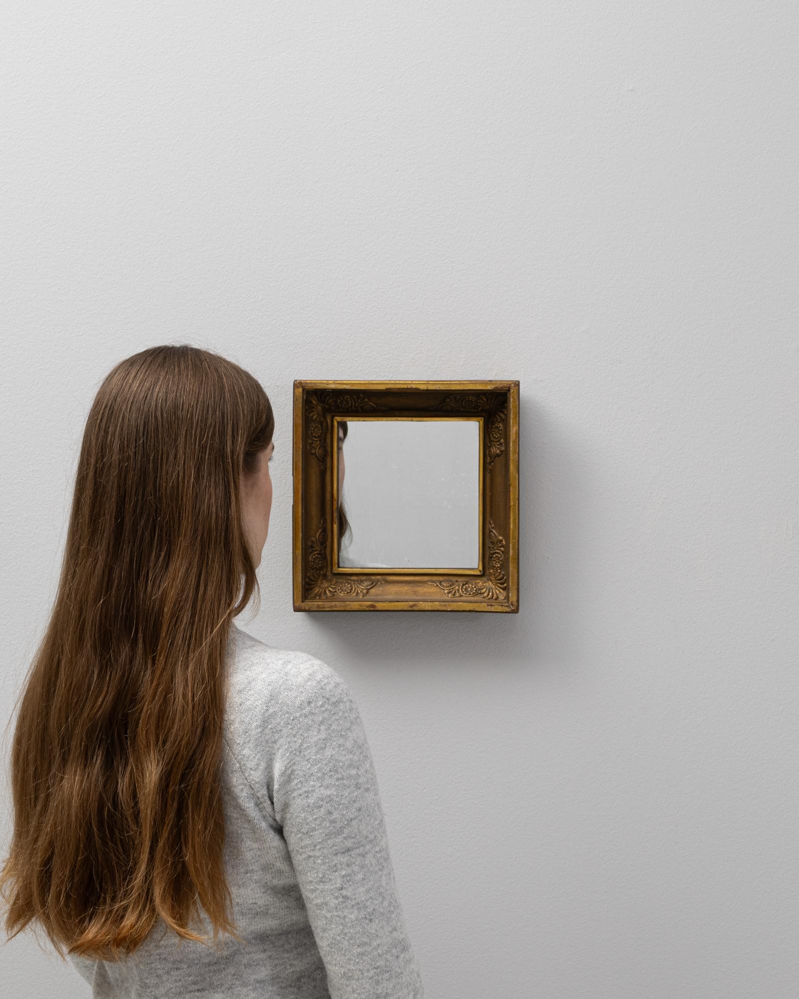This 19th Century French gilded wooden mirror is a sublime example of period craftsmanship and refined aesthetic taste. The ornate frame features intricately carved details reminiscent of Rococo elegance, with delicate scrolling and floral motifs