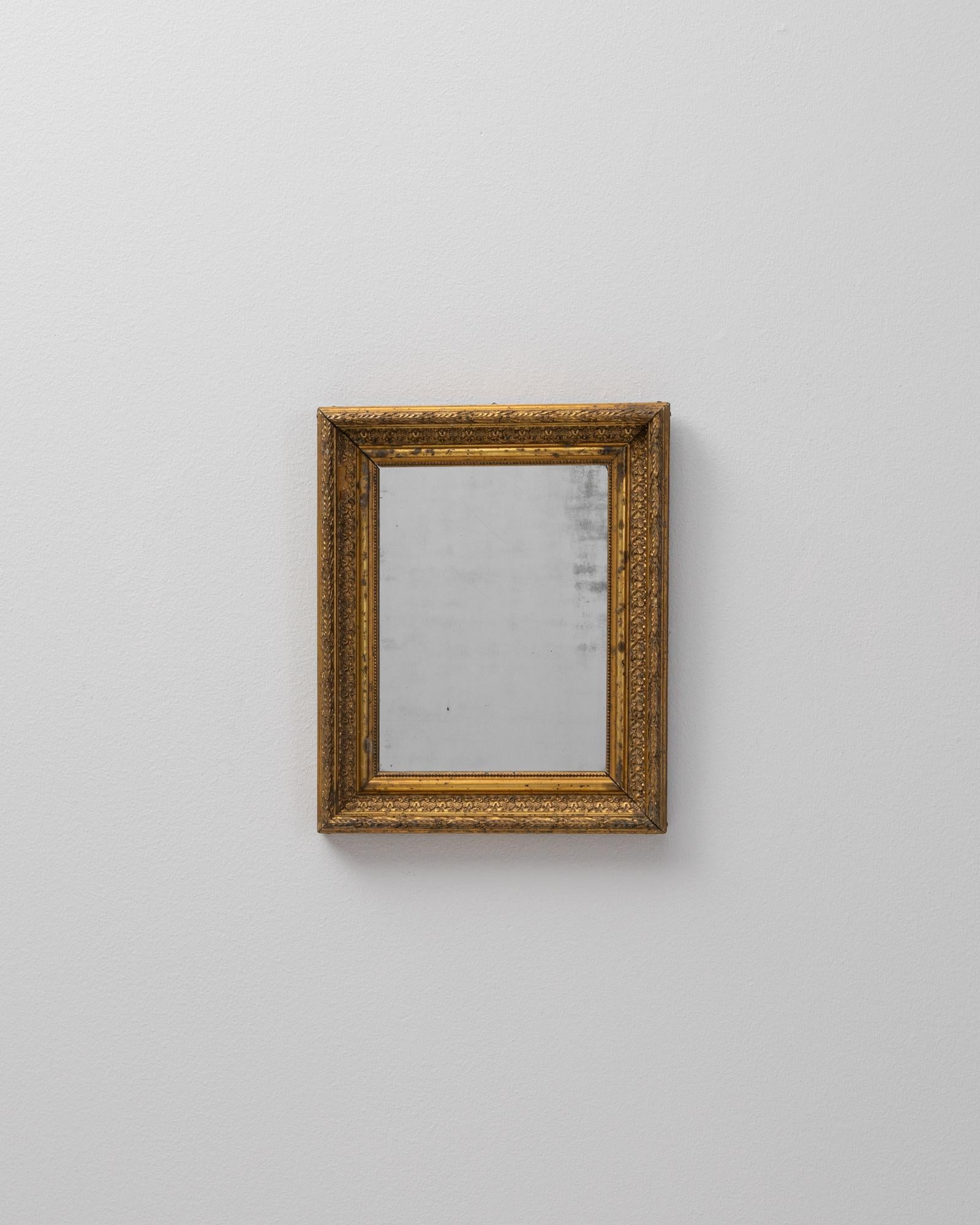 Questo specchio francese del XIX secolo presenta una cornice in legno finemente intagliata e rifinita con una calda doratura consumata dal tempo. La cornice sfoggia motivi decorativi classici, tra cui bordature interne, disegni fogliacei e bordi