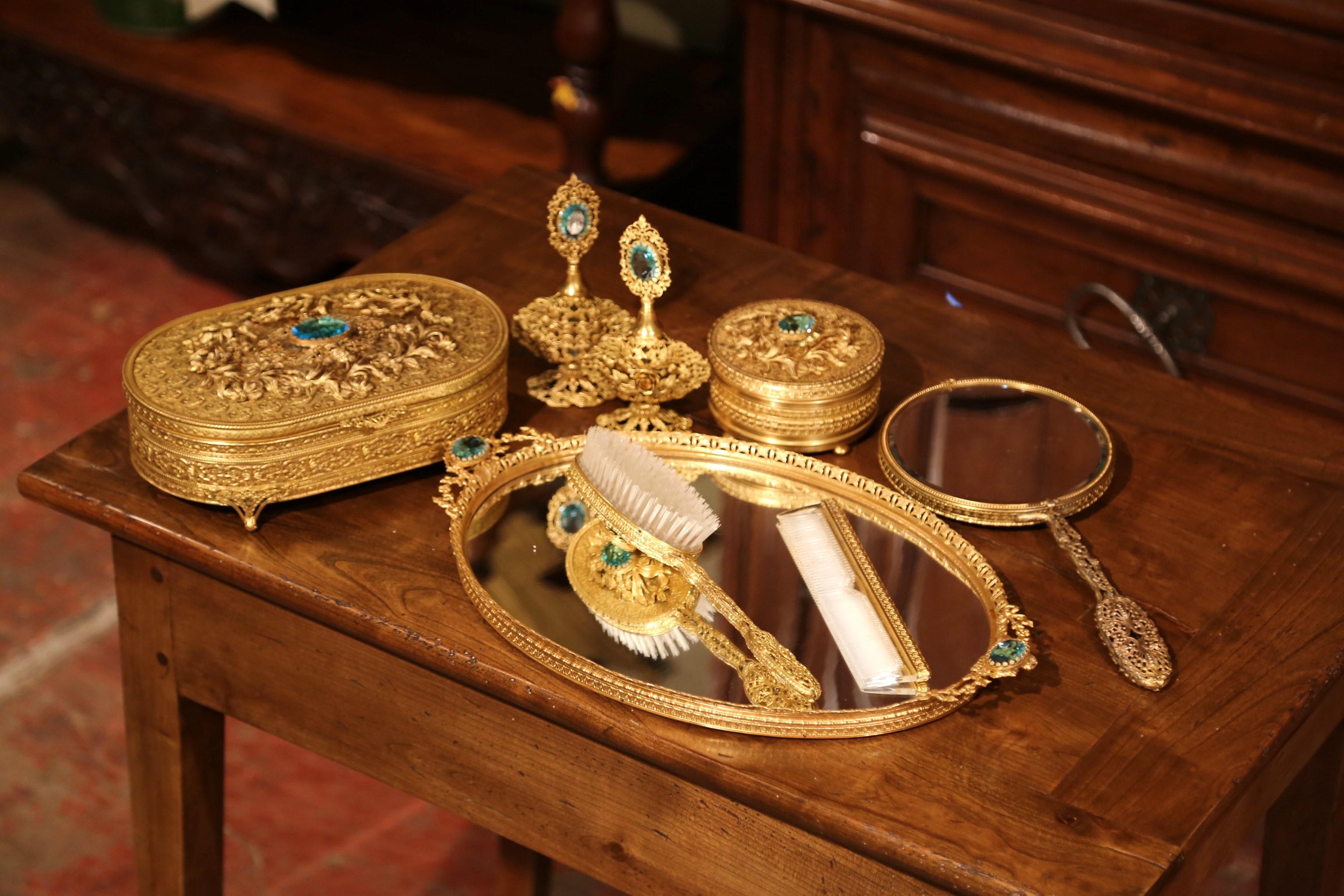 Decorate your master bath with this elegant antique vanity set; crafted in France, circa 1890, each brass piece is heavily decorated with floral and leaf decor in high relief, and embellished with blue-green cut glass medallion. The set includes a