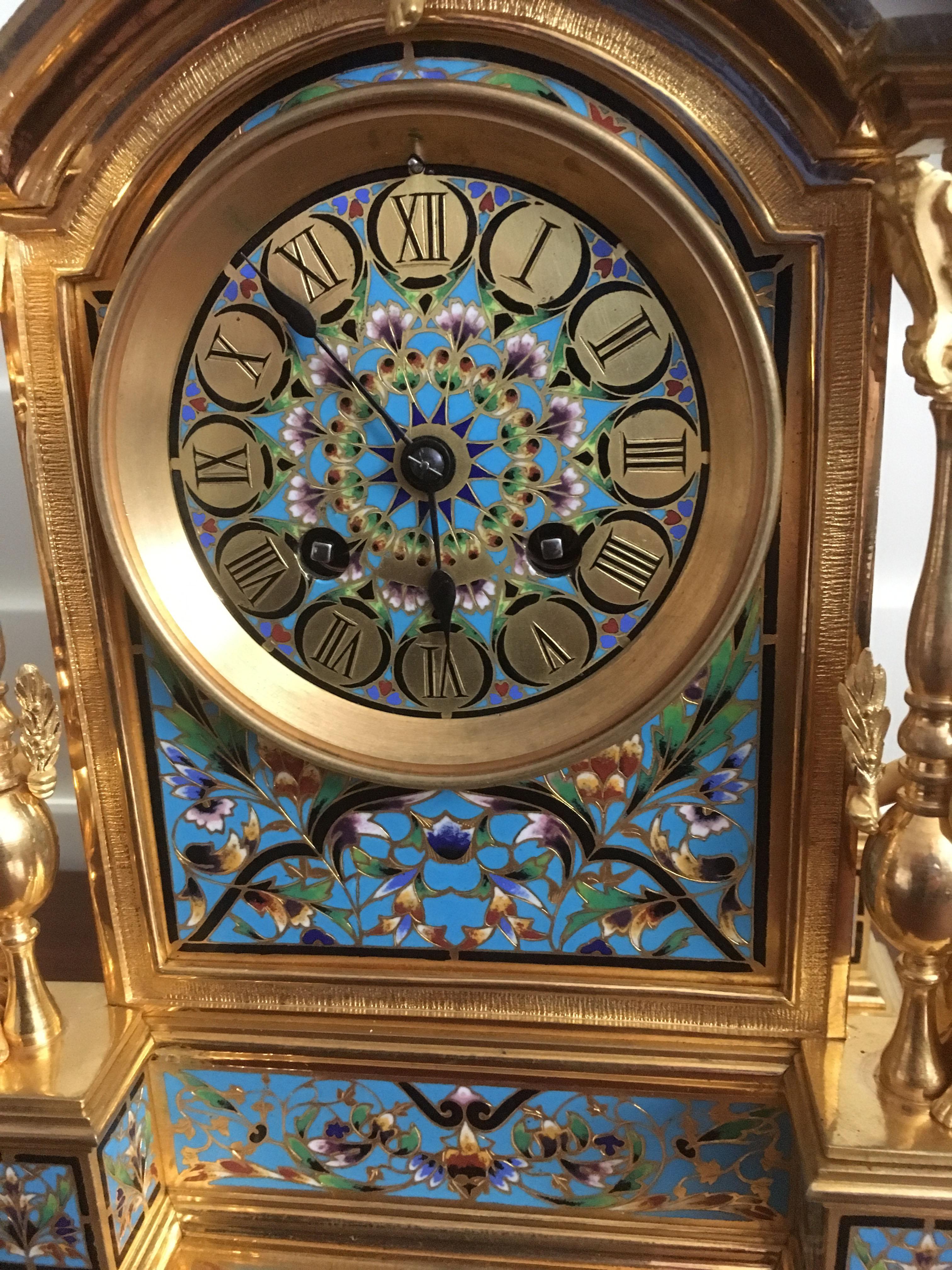 Impressionnante garniture d'horloge de style Renaissance française comprenant une horloge de cheminée et une paire de vases assortis, vers 1870, en bronze doré avec un émail champlevé orné. 

Le boîtier rectangulaire de l'horloge en arc brisé est