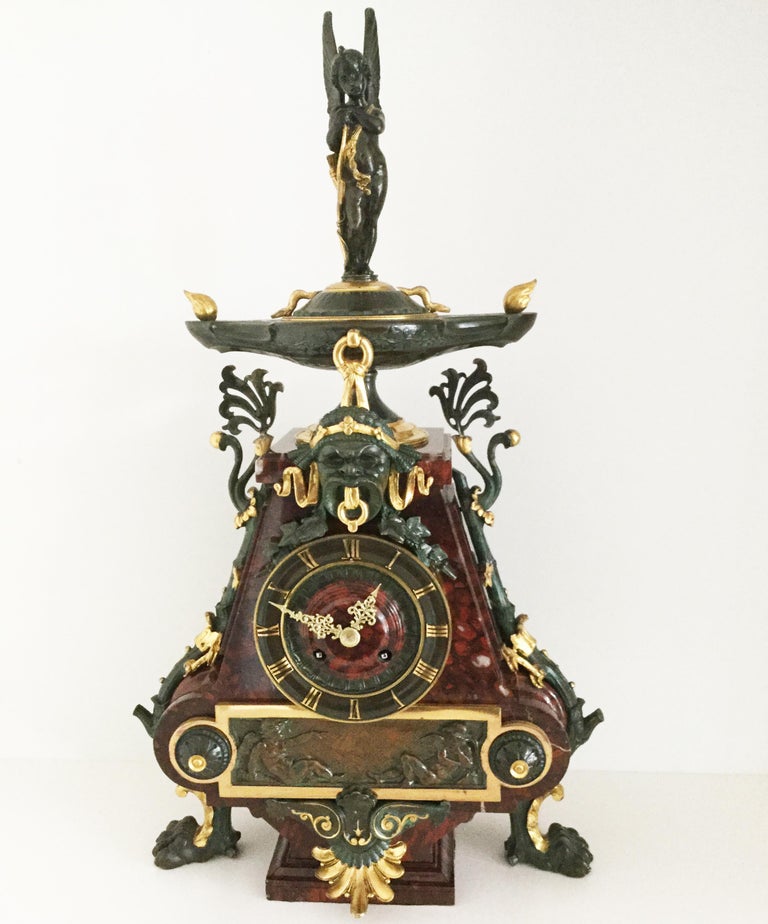 A beautiful 19th century Aesthetic style Charpentier gilt bronze and rouge marble French mantel clock of outstanding quality, circa 1880. The marble case profusely decorated with bronze mounts highlighted in gilt, surmounted by a winged cherub with