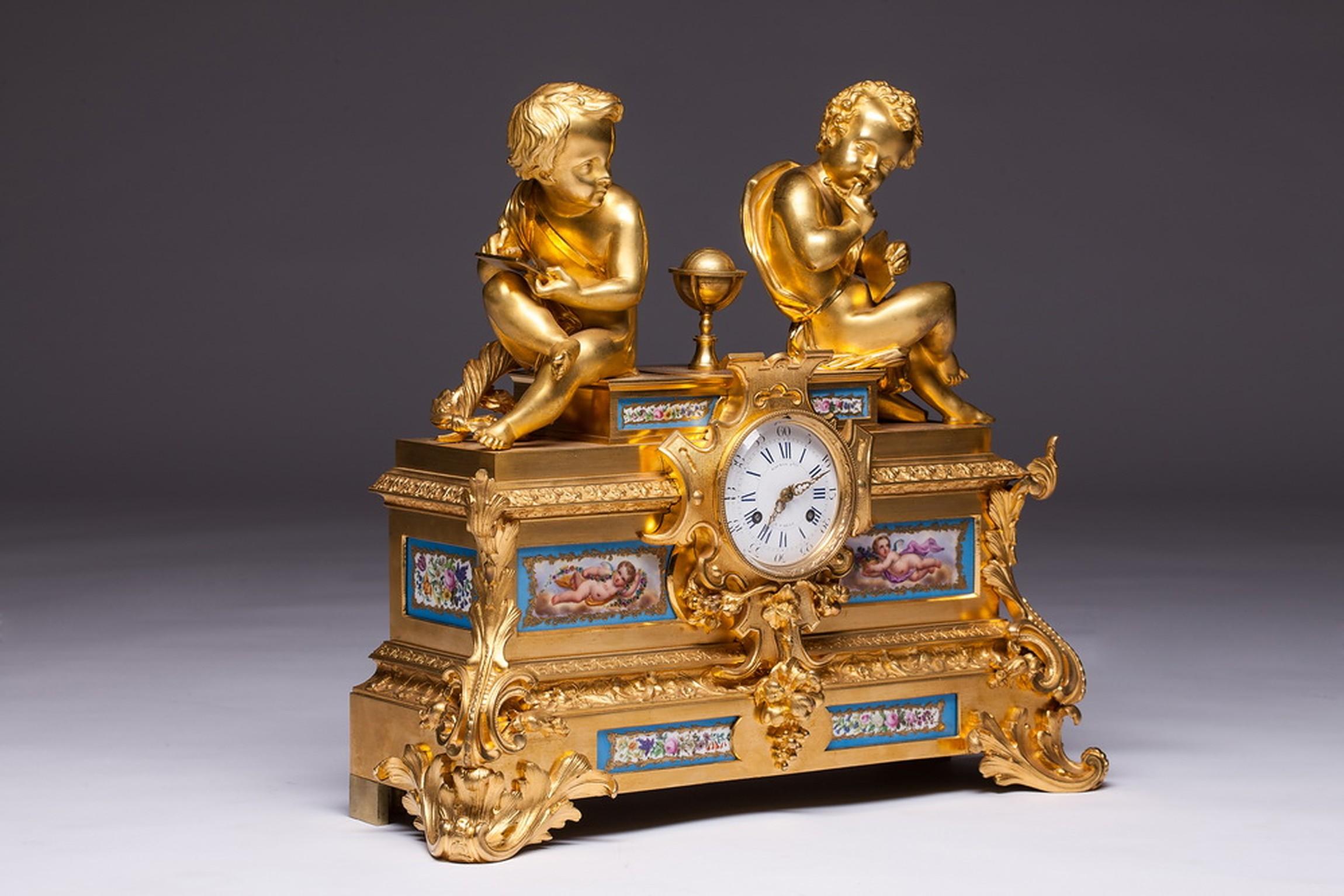 19th Century French Gilt Bronze and Sevres Porcelain Clock By Raingo Freres.
A very fine and early gilded bronze clock mounted with Sèvres porcelain panels. Two seated cherubs sit on each side with a globe besides them.

Raingo was a French