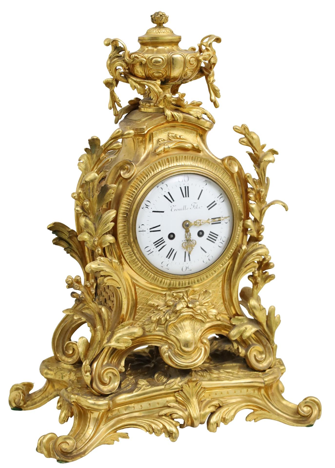 Three piece French gilt bronze clock set, the clock mounted with a foilated urn, white enamel dialed inscribed Crouille Filo, Ameins, ornately cast foliate body resting on rocaille plinth, along with a conforming pari of five light candelabra, 19th