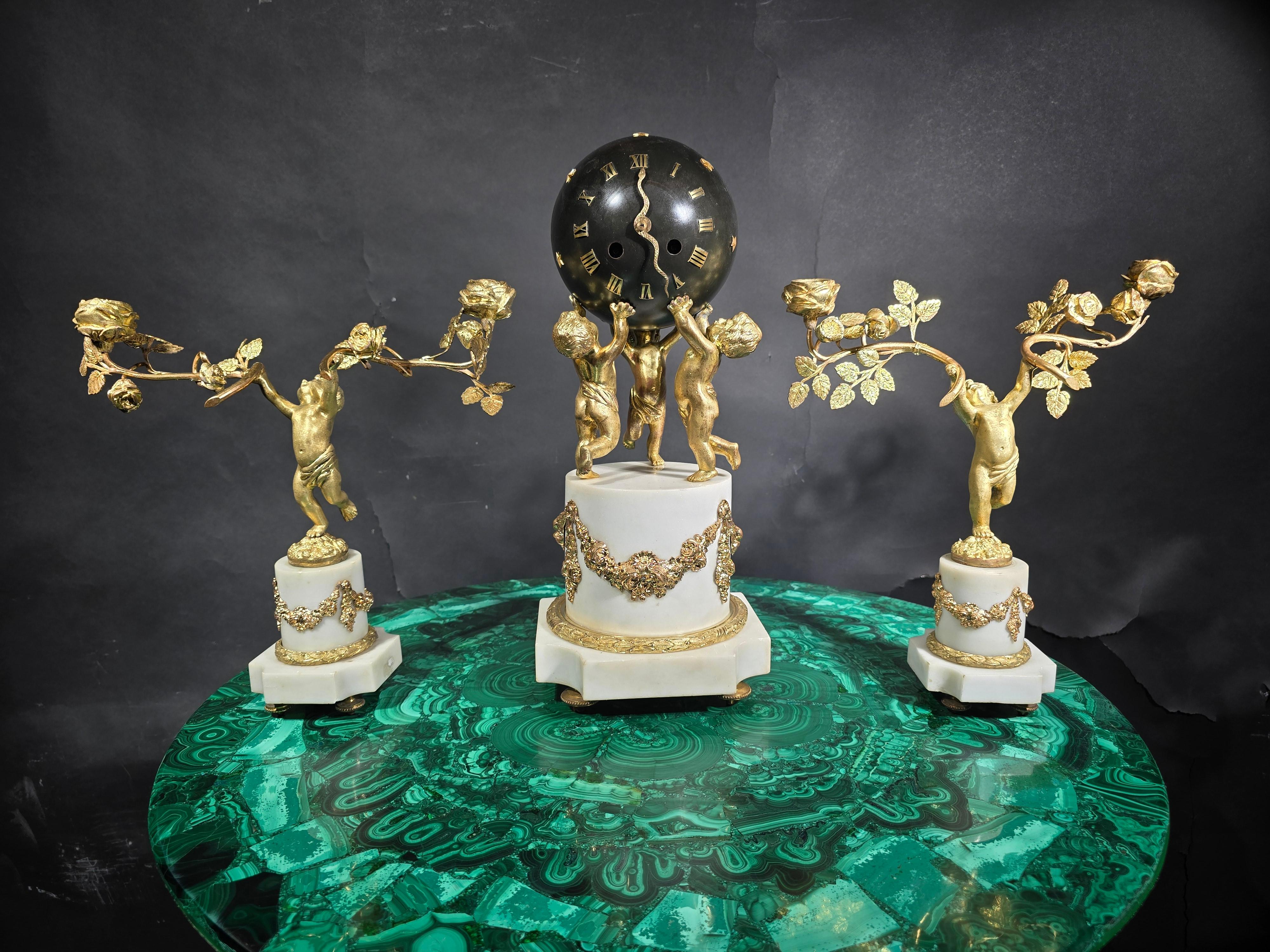 Product Description:

Materials: Gilt bronze and Carrara white marble
Style: 19th Century French
Features: Representation of cherubs holding the terrestrial globe
Clock Dimensions: 40 x 17 x 17 cm
Candelabra Dimensions: 35 x 30 x 15 cm
Features and