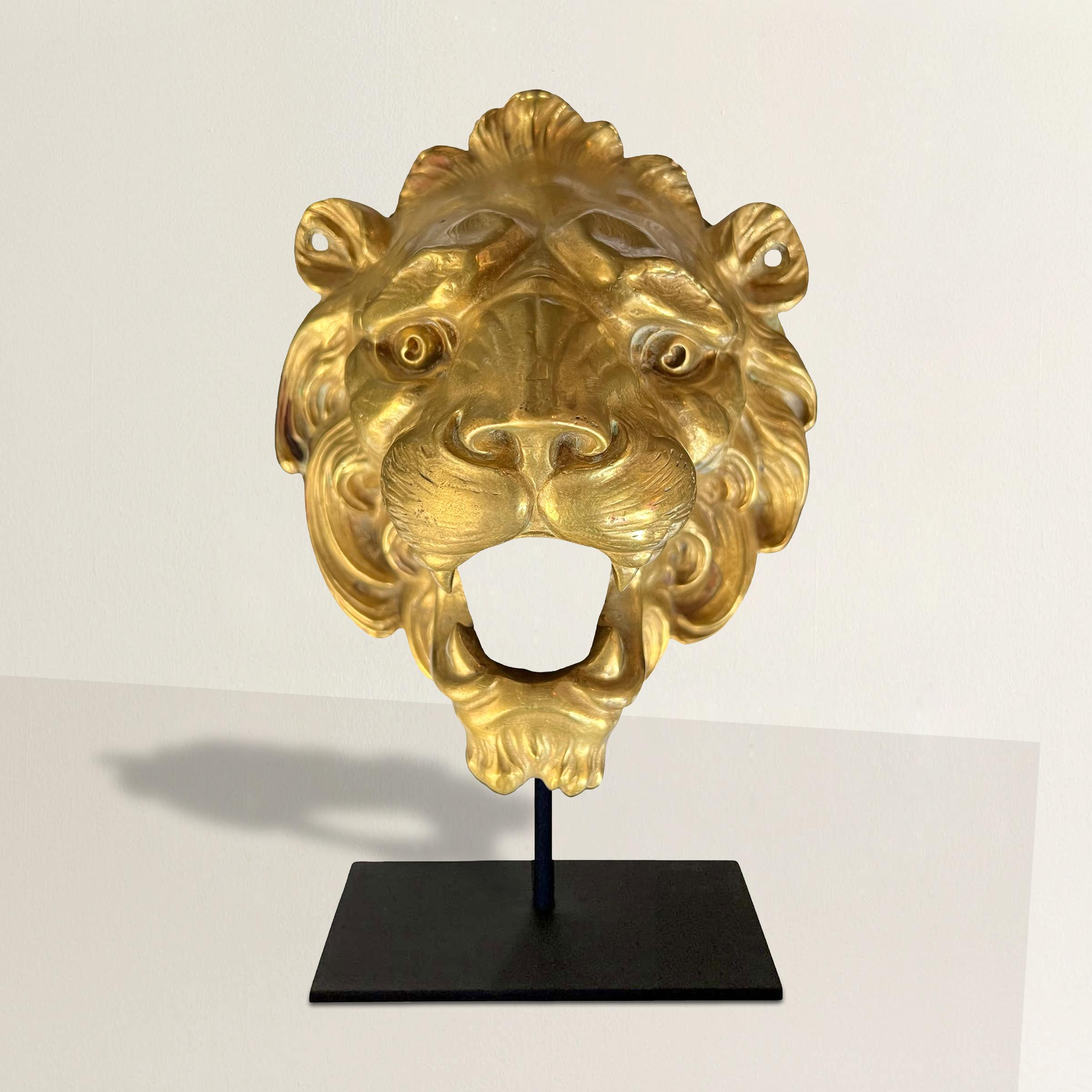 Behold this exquisite 19th-century French gilt bronze lion head architectural fragment, a mesmerizing relic of a bygone era. This captivating piece features a majestic lion with an open mouth, revealing intricately detailed teeth, surrounded by a