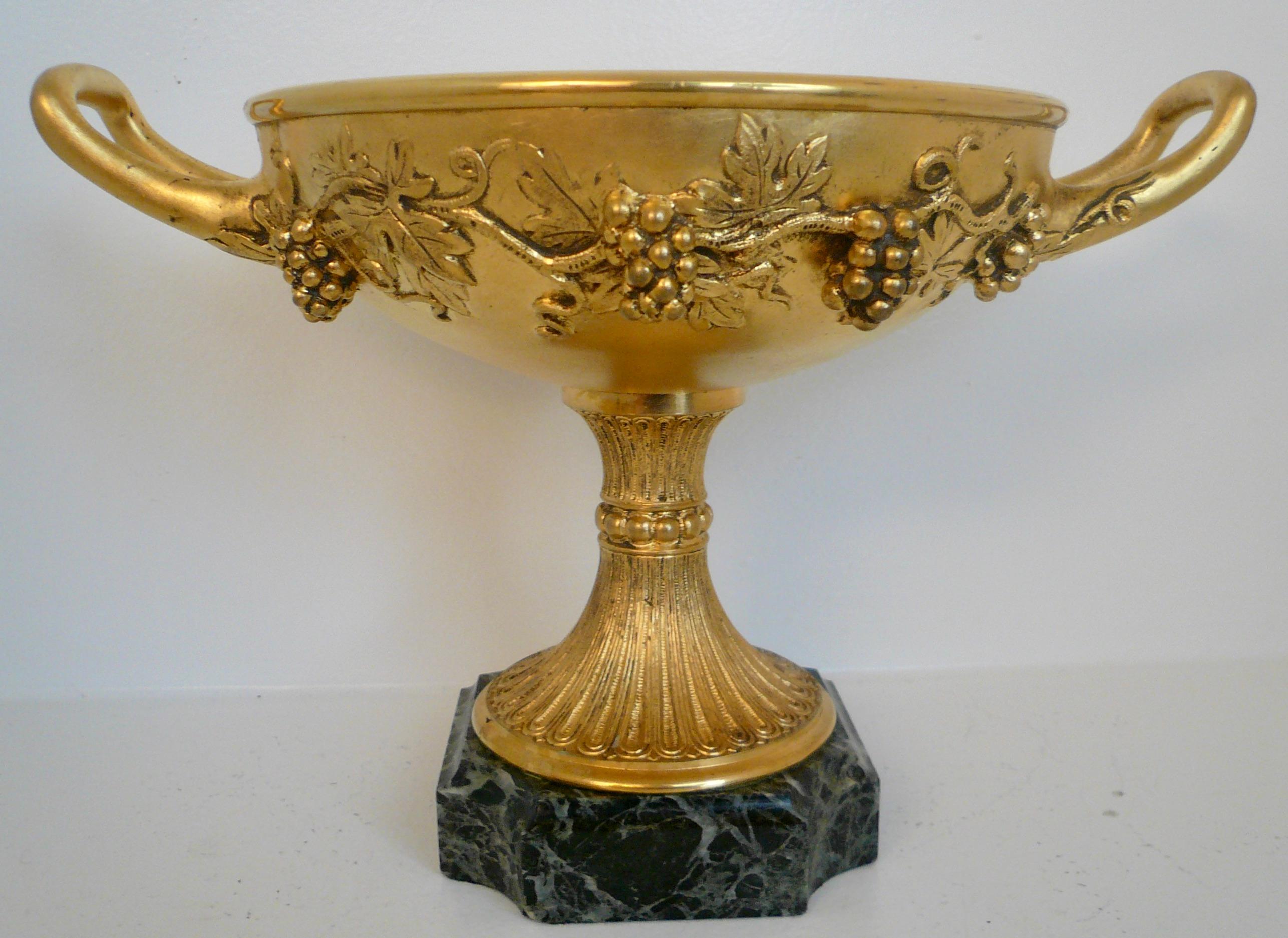 This finely detailed gilt bronze compote features a border of vintage motif including grapes and grape leaves. The compote is mounted on a verde antique marble base.