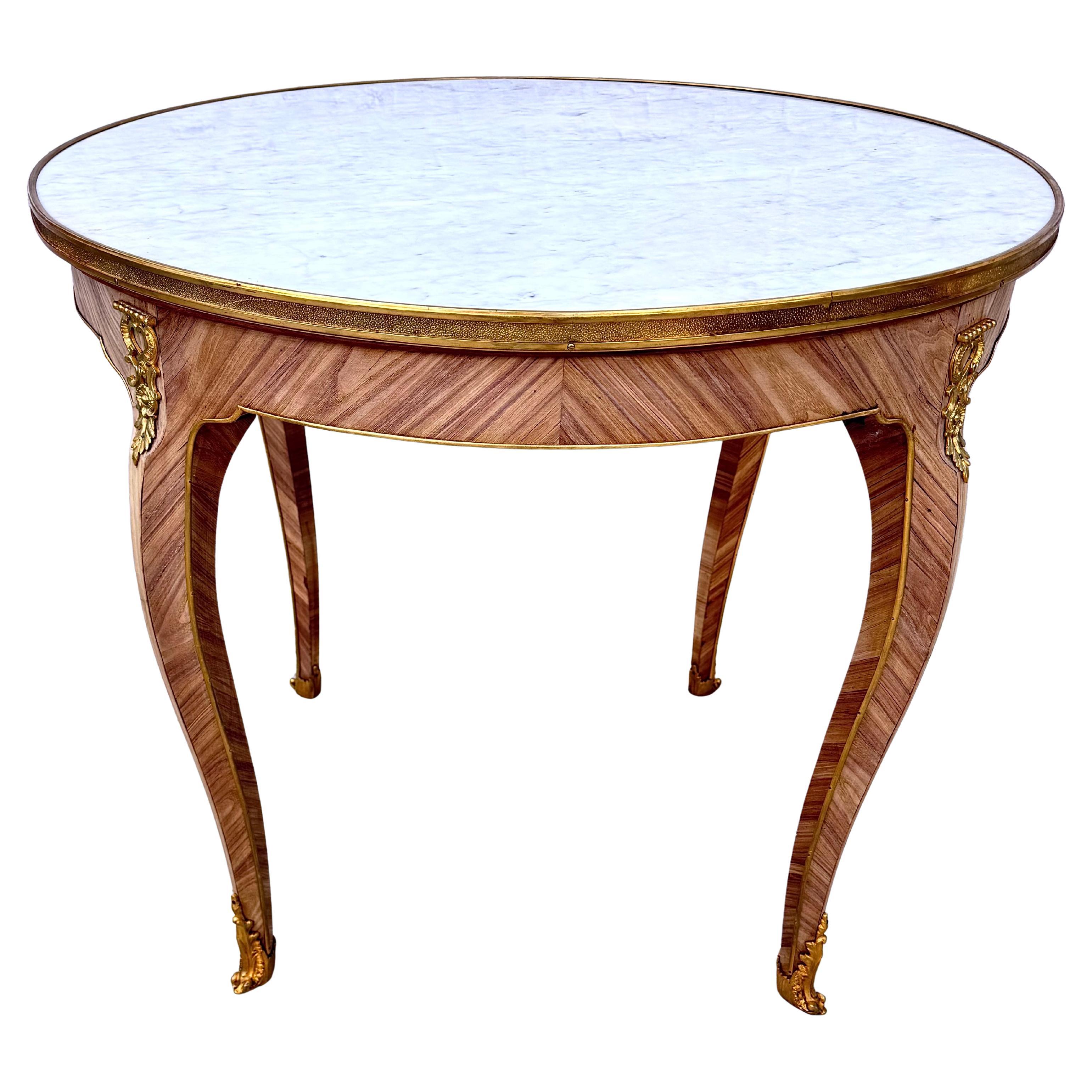 Exquise table d'appoint ronde en bronze doré et marbre blanc du 19ème siècle. La table est ornée d'une garniture décorative en bronze doré sur le pourtour et de motifs de feuilles à enroulement en bronze doré sur le haut des pieds et les pieds de la