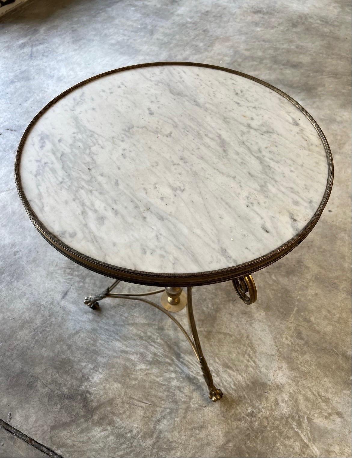 A fine quality french gilt bronze and white marble gueridon table with impressive casting to lower flame finial, hair paw feet on casters. True period piece with a neoclassical urn to the lower element of the table. 