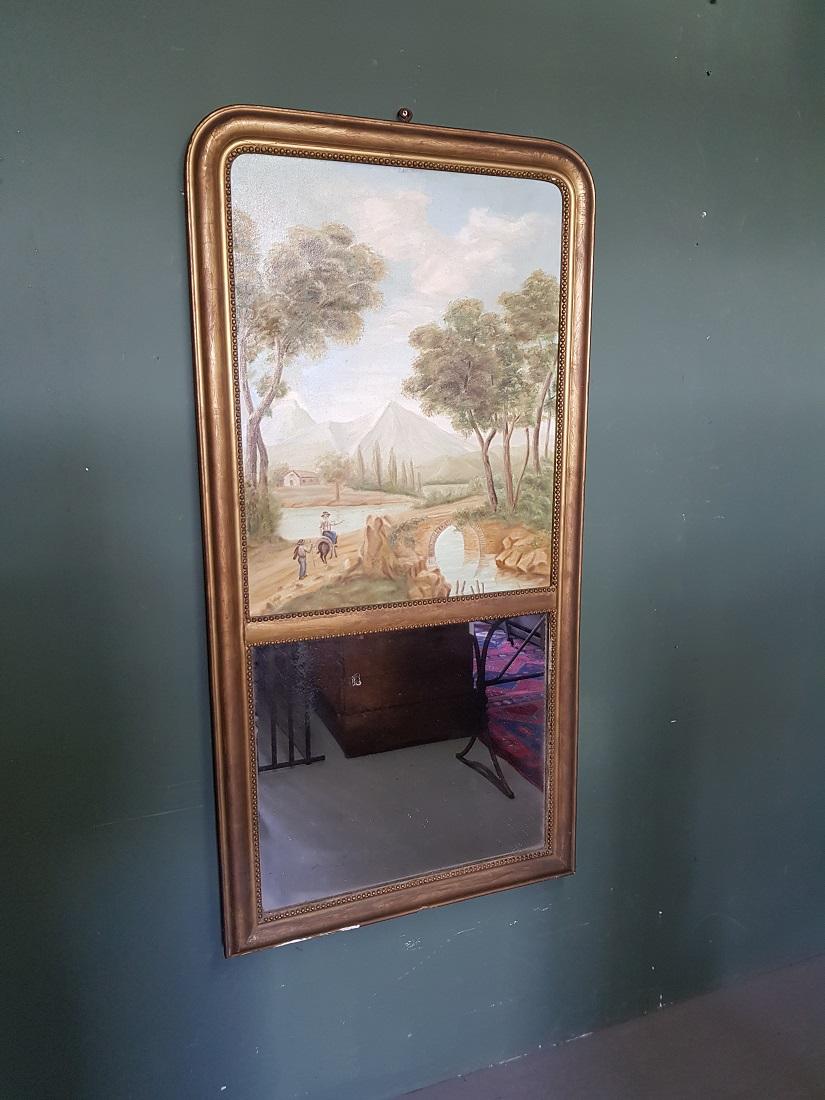 Antique French gilt mirror with in the upper part a painting with a representation of people at a bridge in a mountain landscape, it has some damage around the age but nothing serious. Originating from the 2nd half of the 19th century.

The
