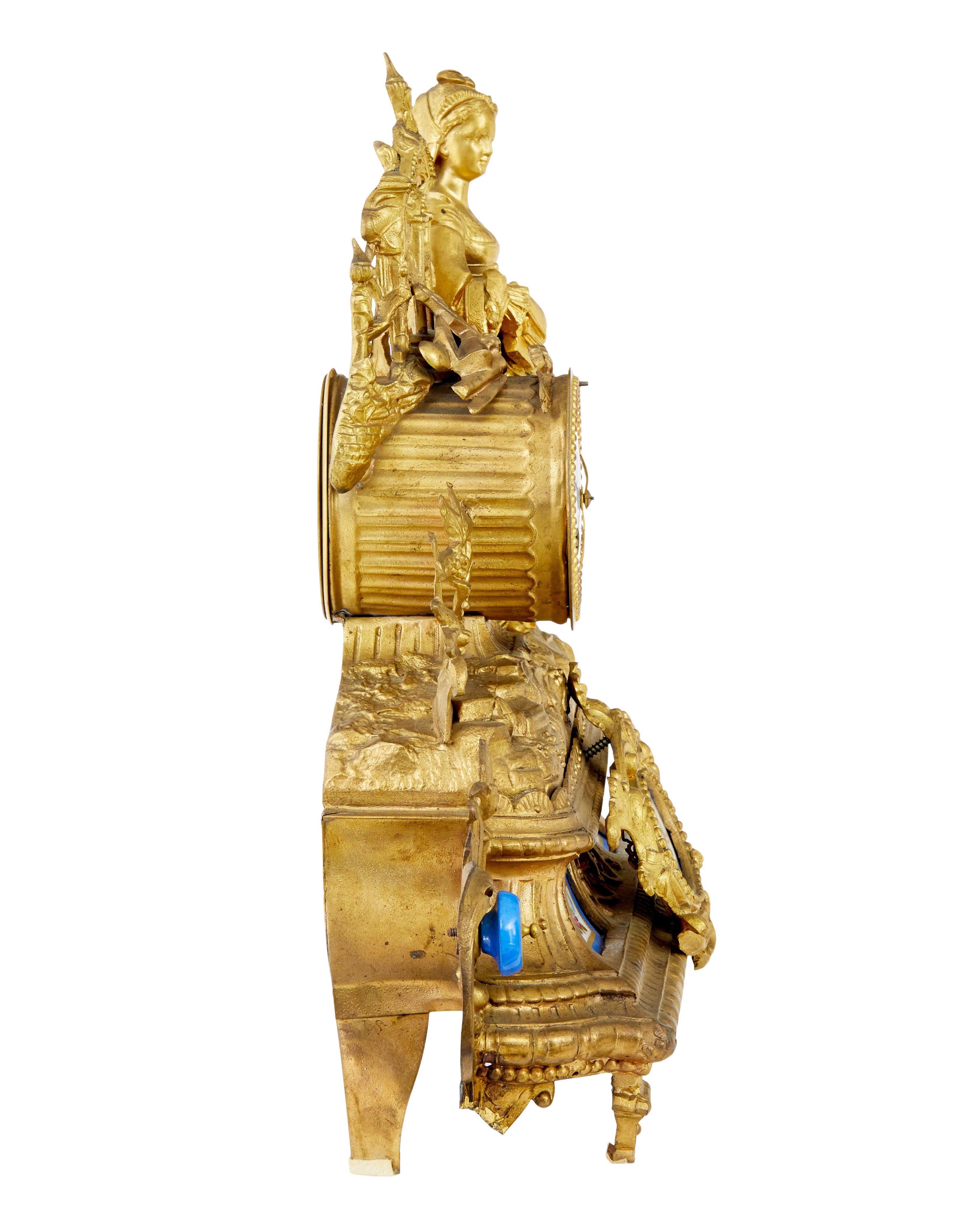 19th century French gilt mantle clock with sevres plaques circa 1890.

Fine quality ornate french clock surmounted with a lady in traditional french dress leaning on an architectural window and ship building tools.  Enamel clock face with roman