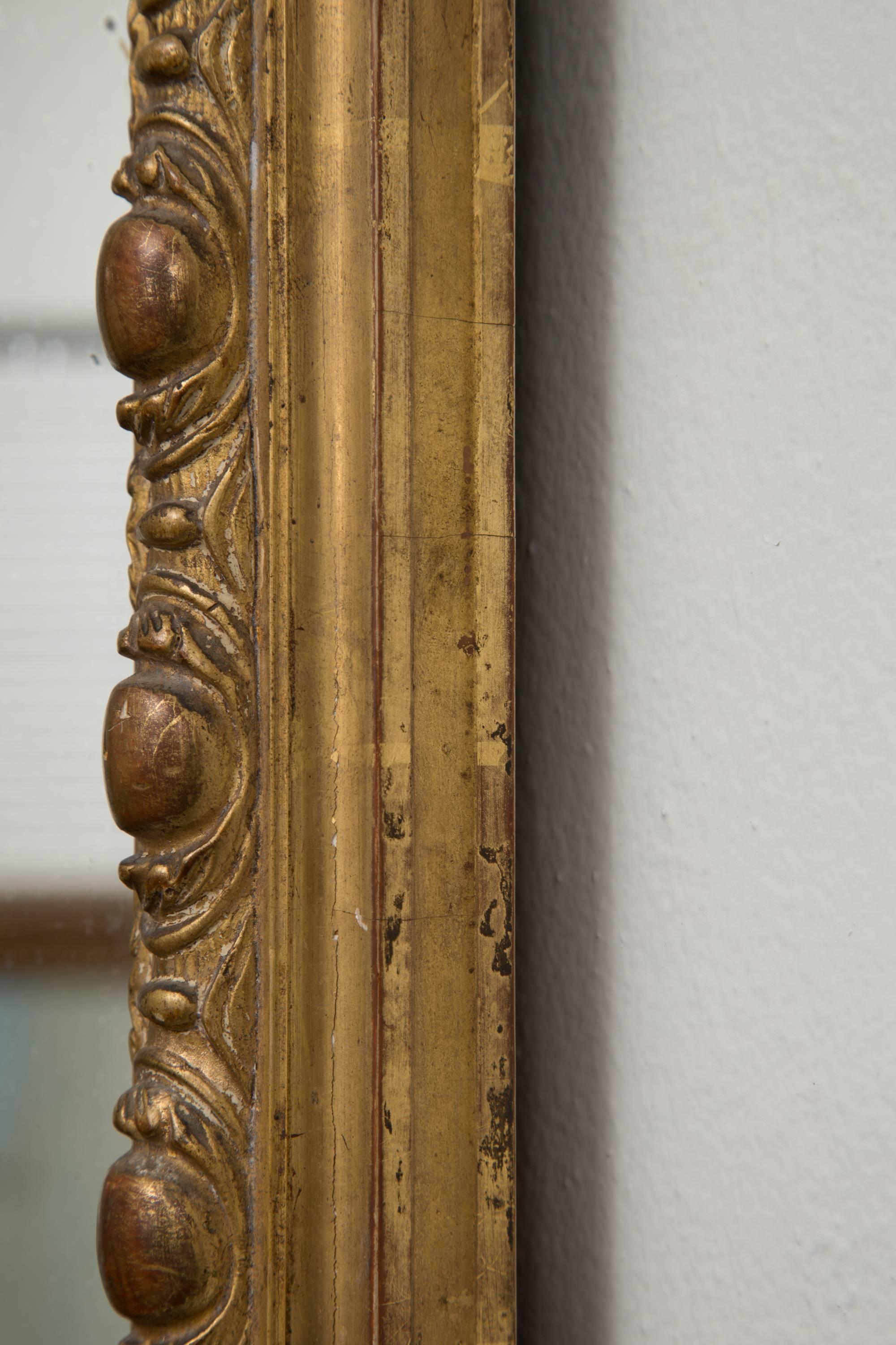This is a formal French mirror with a pierced ornate cornice above a mirror plate framed by a mirrored border edged with bead molding and ornate corner embellishments, circa 19th century.