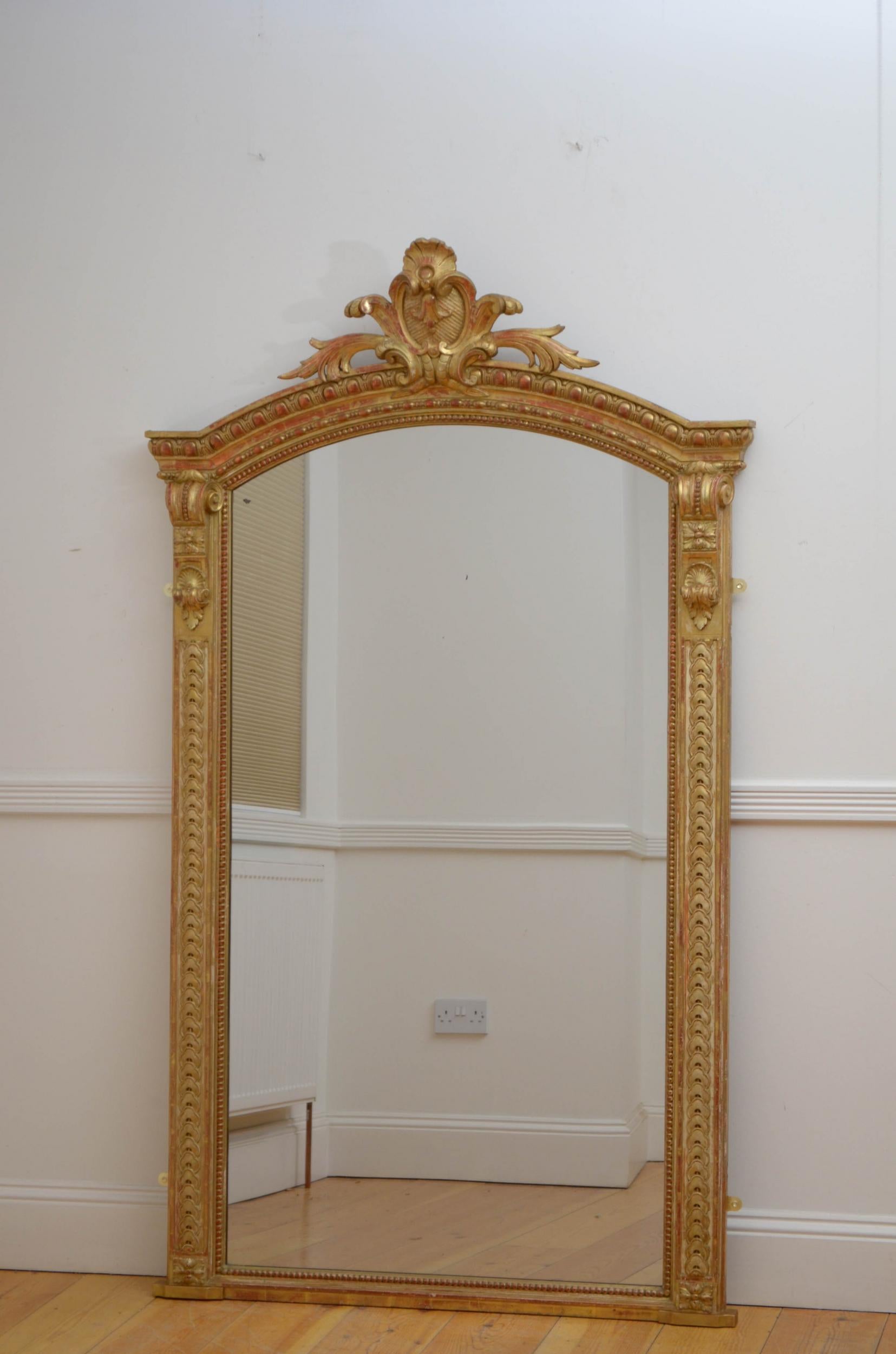 Sn4993 a tall XIXth century giltwood mirror, having original glass with some imperfections in moulded and carved frame with floral crest to centre flanked by highly decorative drop carvings. This antique mirror retains its original glass, original