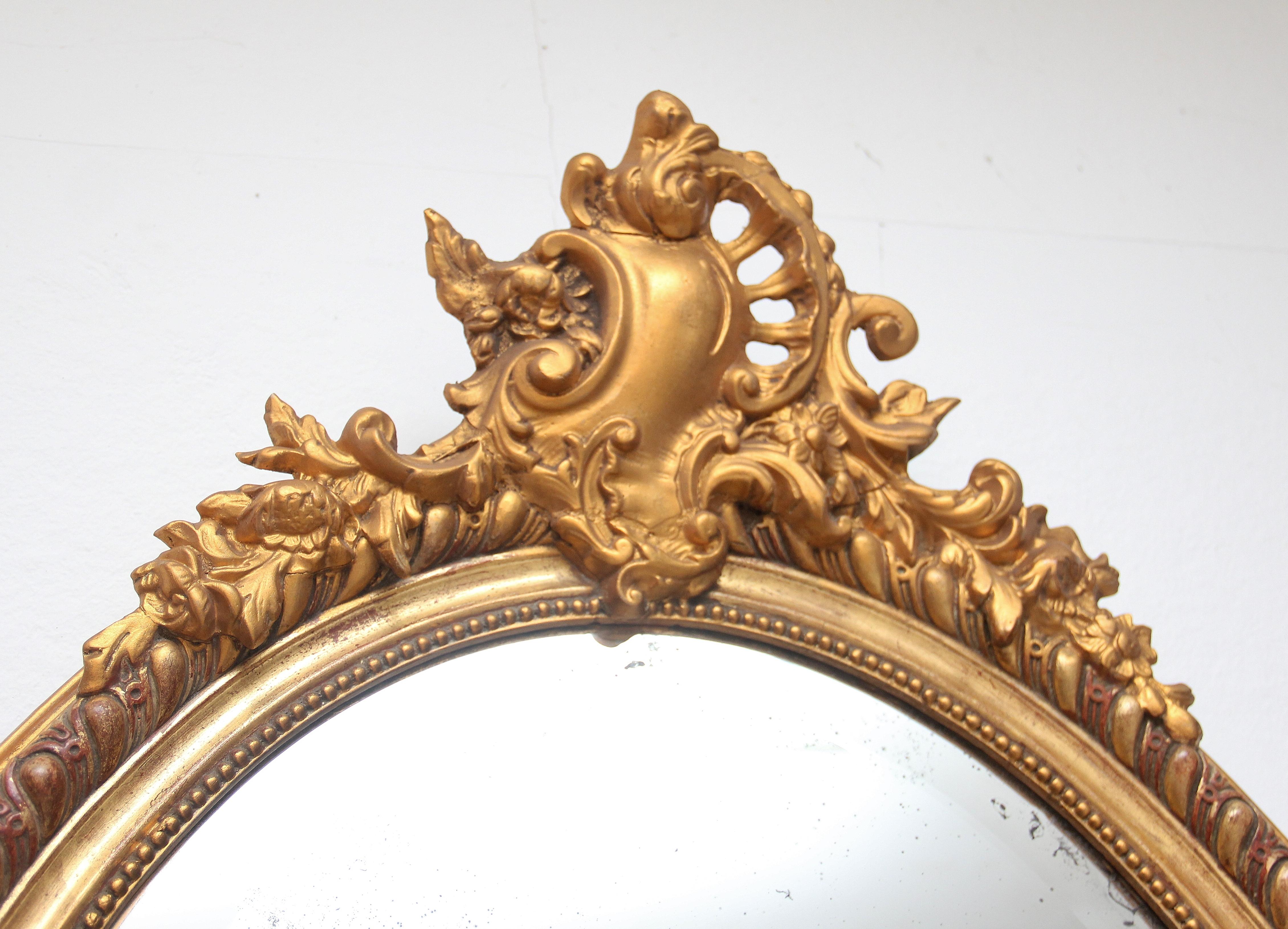19th Century French gilt oval wall mirror, highly decorative and having an impressive oval frame with intricate decorative beading running around the inner edge and further carved decoration on the outer edge, bold floral carving at the top of the