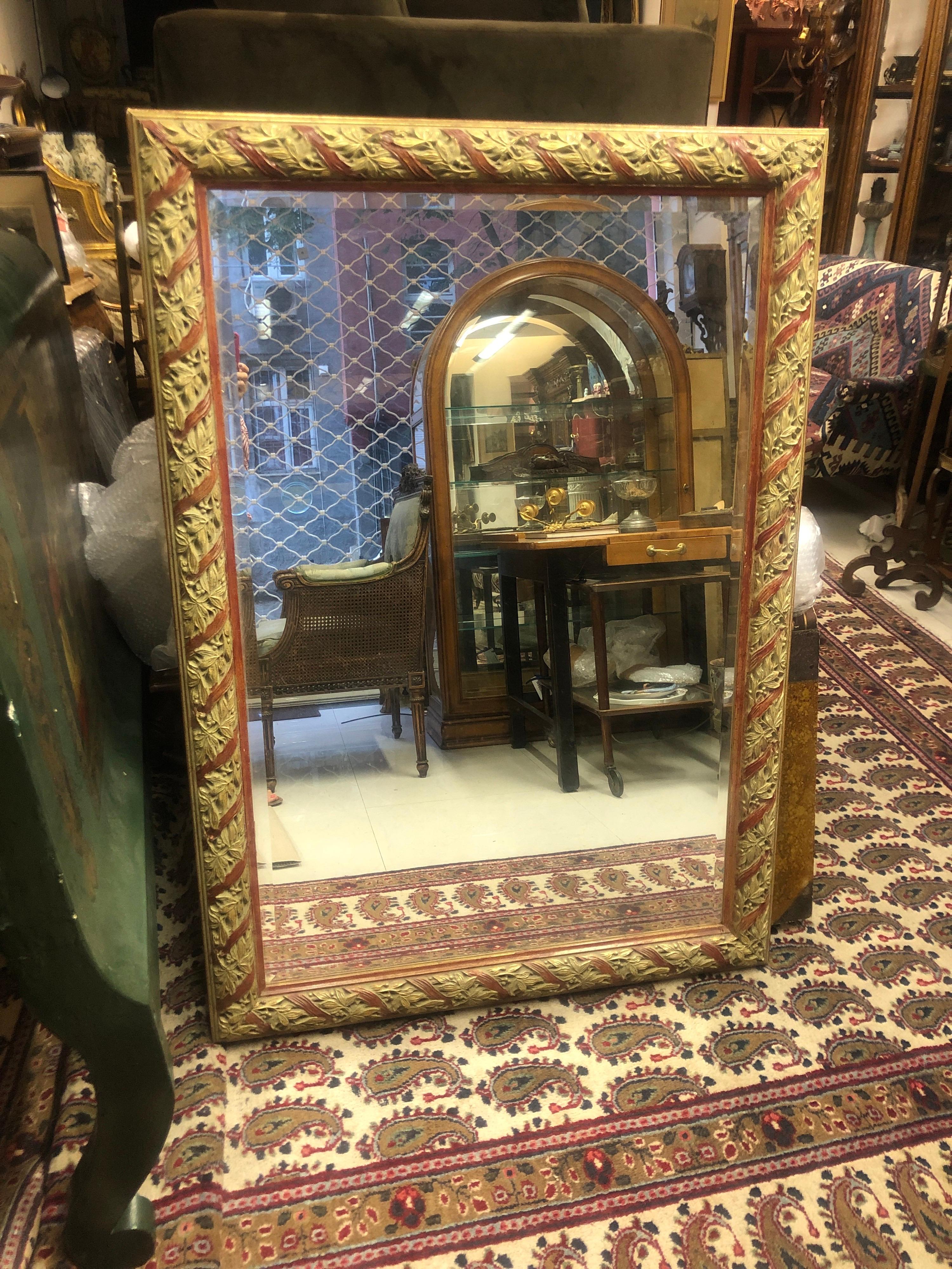 Large French gilt wood mirror with beautiful hand carved decoration and red hand painted accents.
France, circa 1870.