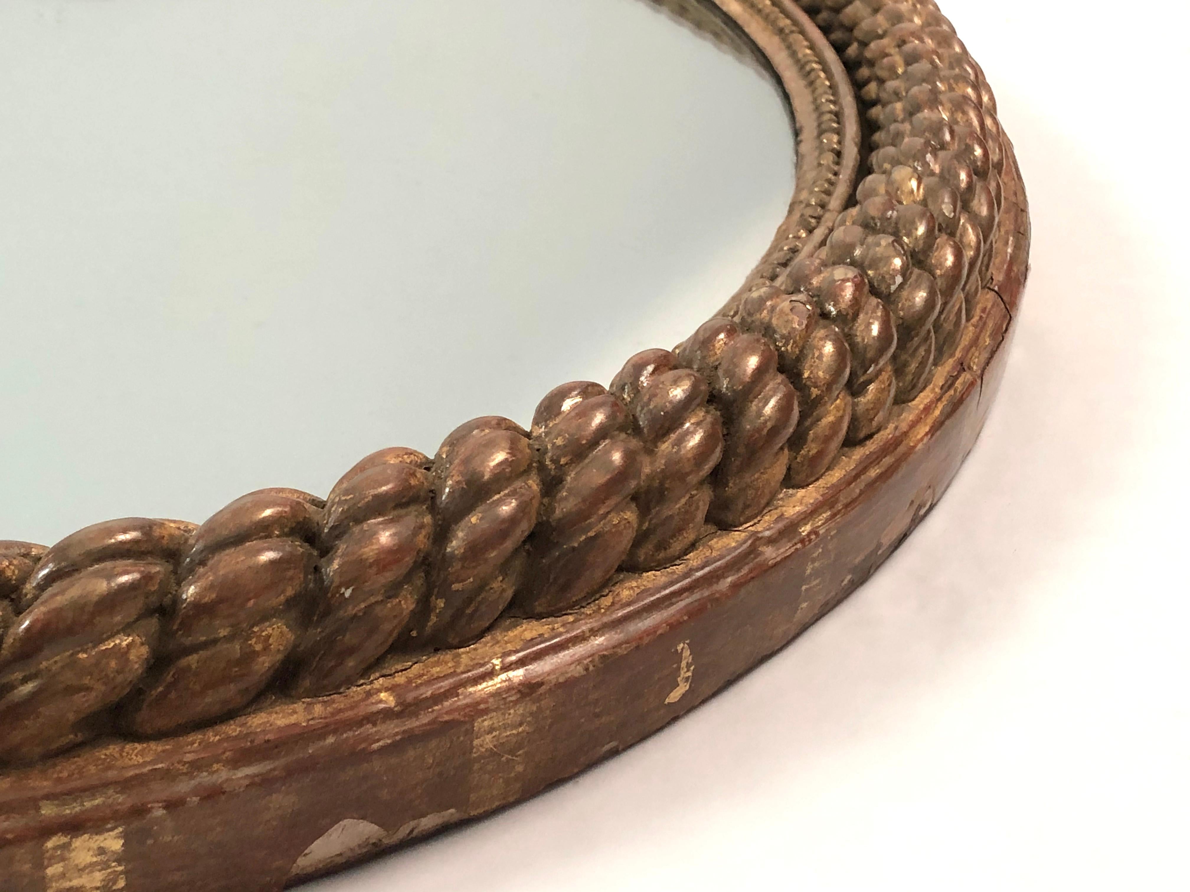 A beautifully detailed 19th century French oval giltwood mirror with deeply carved and gilded rope decoration around the perimeter, with a second smaller string of pearls border next to the original mirror glass.
Provenance: A William Hodgins