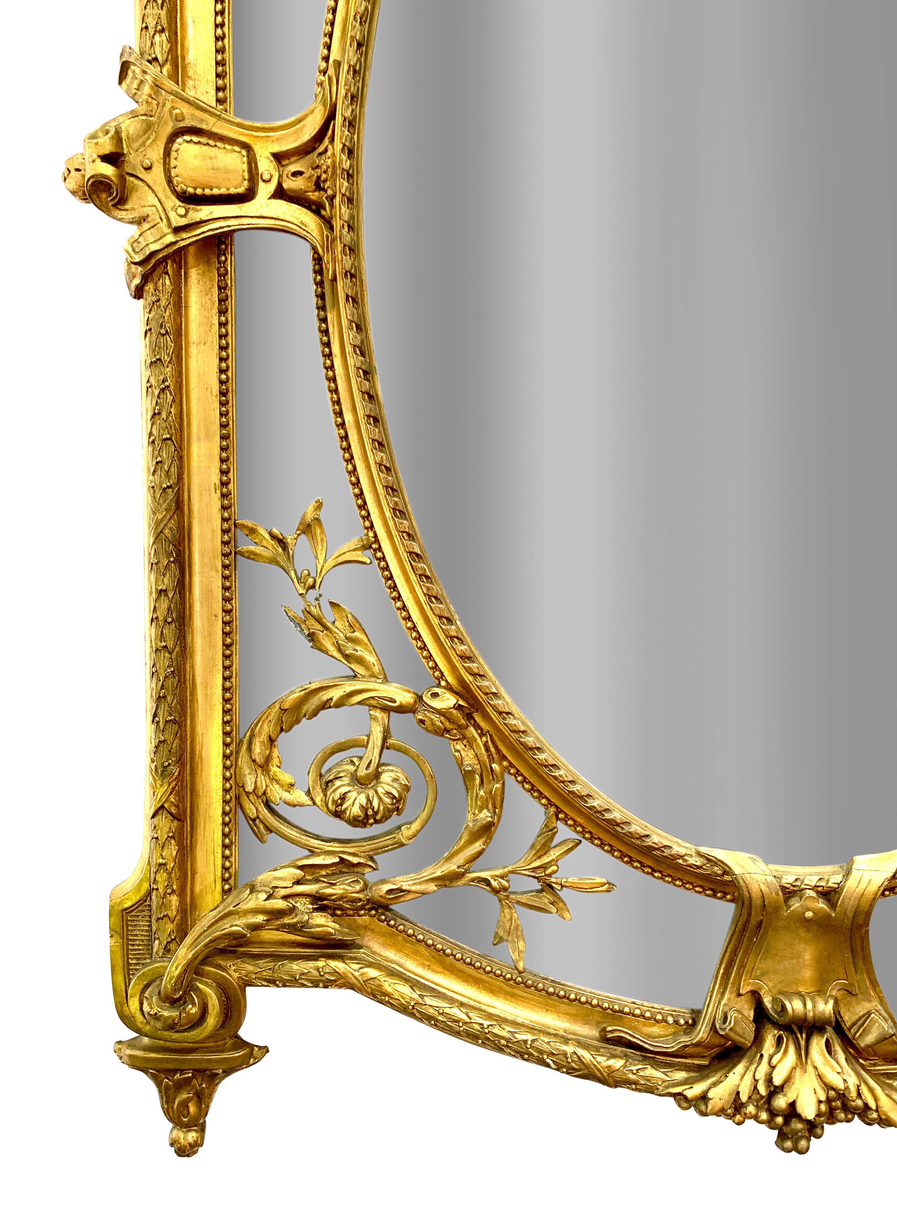 Exceptionnel miroir ancien français de style Louis XVI en bois doré et gesso. La plaque cintrée sous une crête élaborée d'ornements à volutes et de fleurs avec deux chérubins ailés magnifiquement sculptés soutenant une plaque centrale ovale avec un
