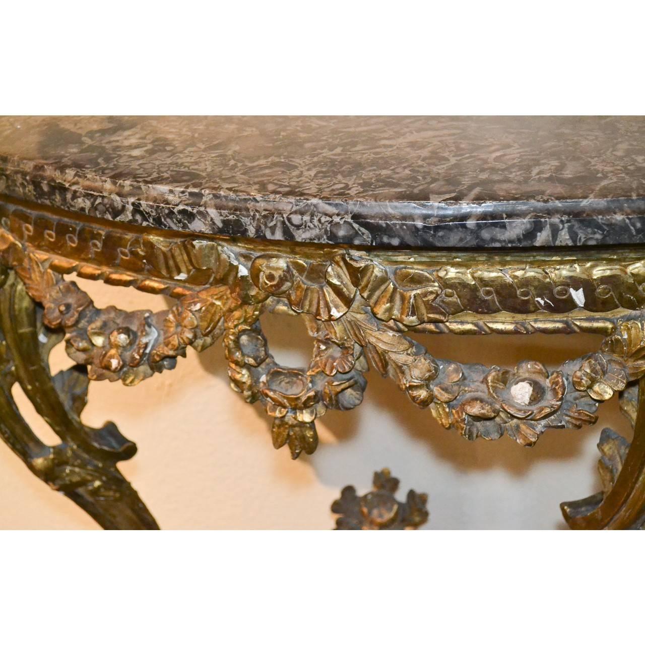 Fabulous 19th century French giltwood console table with an exquisite marble top. (See closeup photo of marble). The base ornately hand-carved with garland swags. The beautifully contoured legs end in carved hoof feet held by a stretcher with an urn