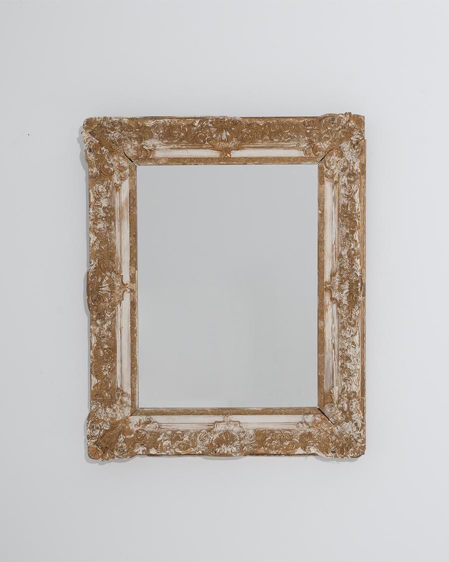 This antique French mirror offers an elegant 19th century design in giltwood. Made in the 1800s, carved rosettes adorn the corners of the frame, while intricate patterns of beading and geometric leaves border the sides. The frame has been carefully