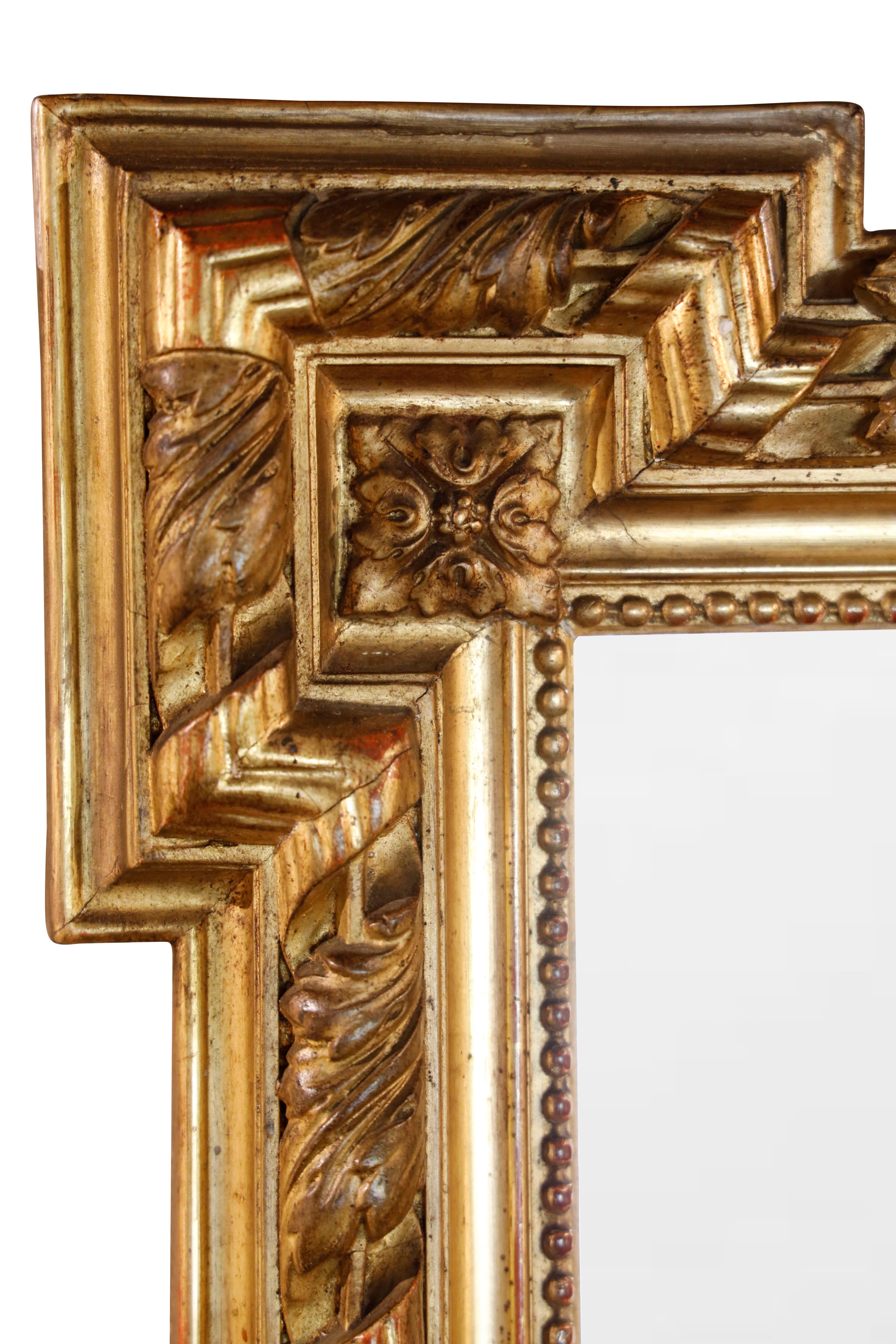 Miroir en bois doré français du 19ème siècle avec verre d'origine.  Cadre en bois doré à sculptures moulurées et biseautées décorées de motifs de feuillage et d'une crête centrale en forme de feuille.