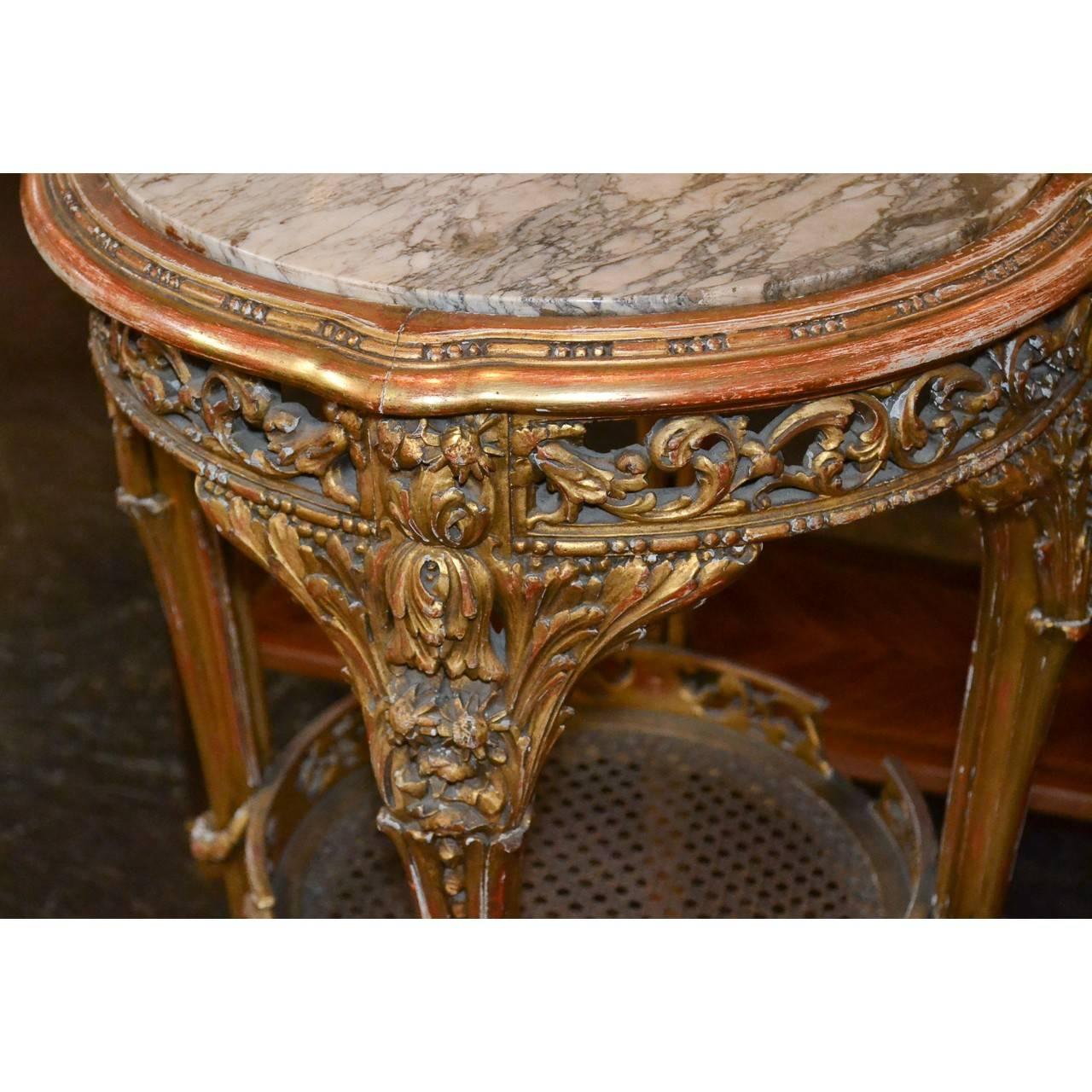 Very fine 19th century French giltwood and marble top side table or pedestal. The ornately carved apron with scrolled and stylized acanthus leaves. The sleek contoured legs with thistle wreath accents held by a caned lower tier with a carved