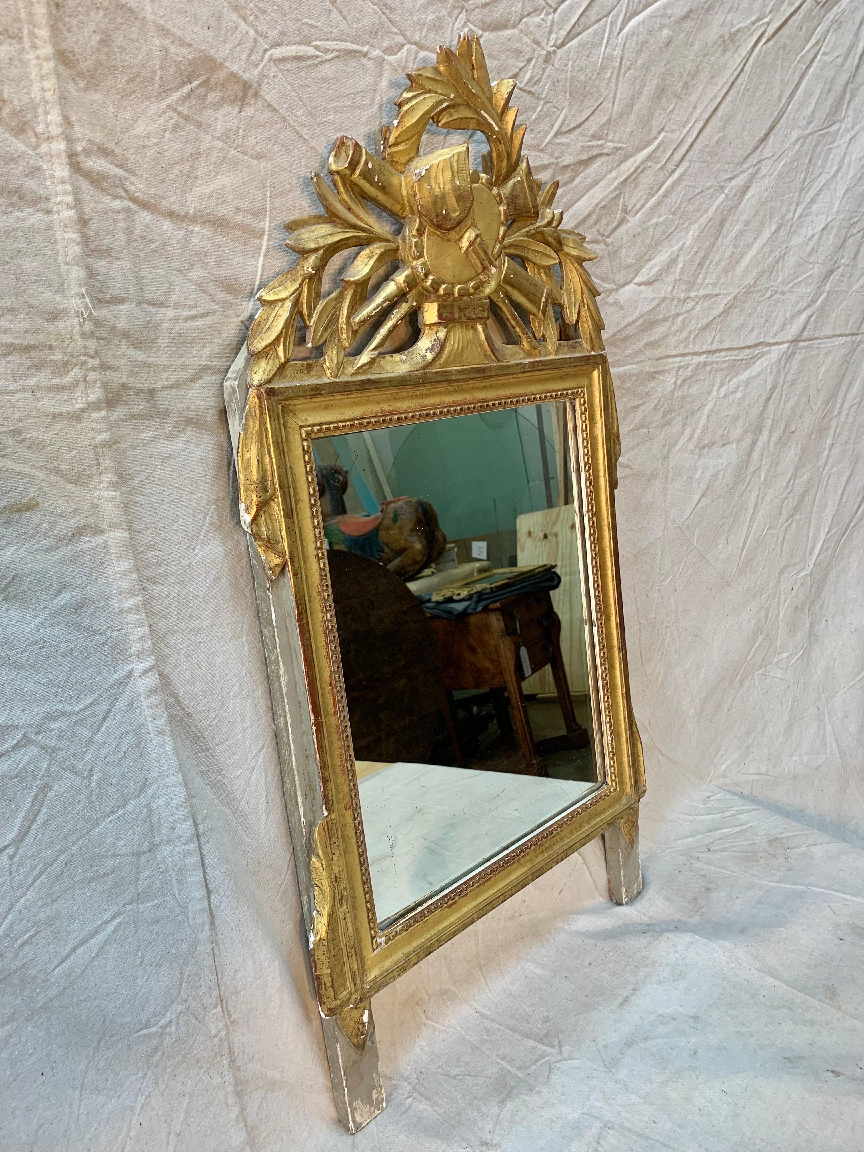 Presented as found, this beautiful Mid 19th Century Carved and Gilded French Wall Mirror features a decorative motif and details of foliage. The mirrored glass has some spotting and crazing which adds to the patina of the piece. Newly wired and