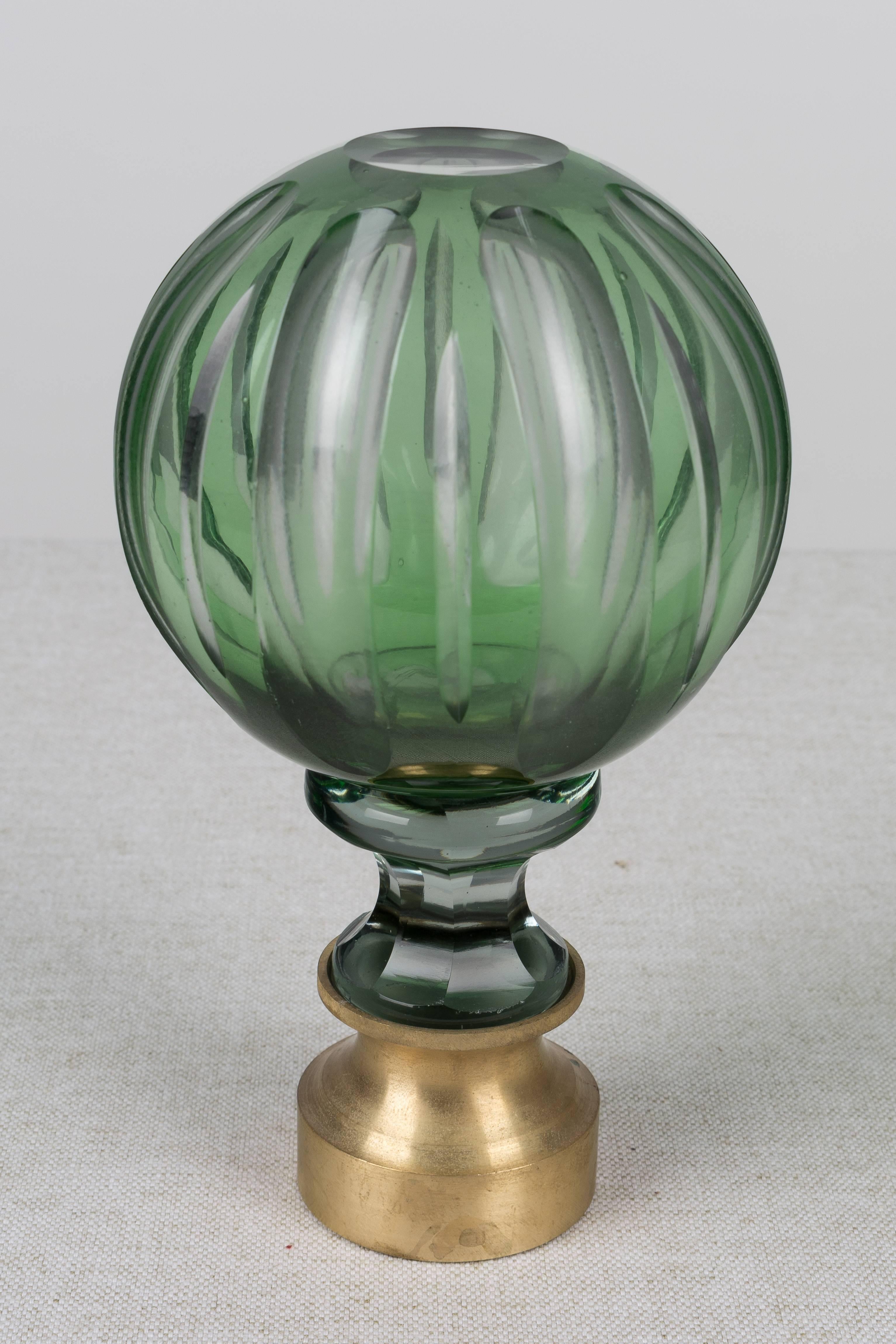 A 19th century French crystal newel post finial or boule d'escalier. Made of two layers of cased glass with the green glass surface cut back to the clear glass underneath. Brass hardware base. These wonderful finials were used as decorative elements