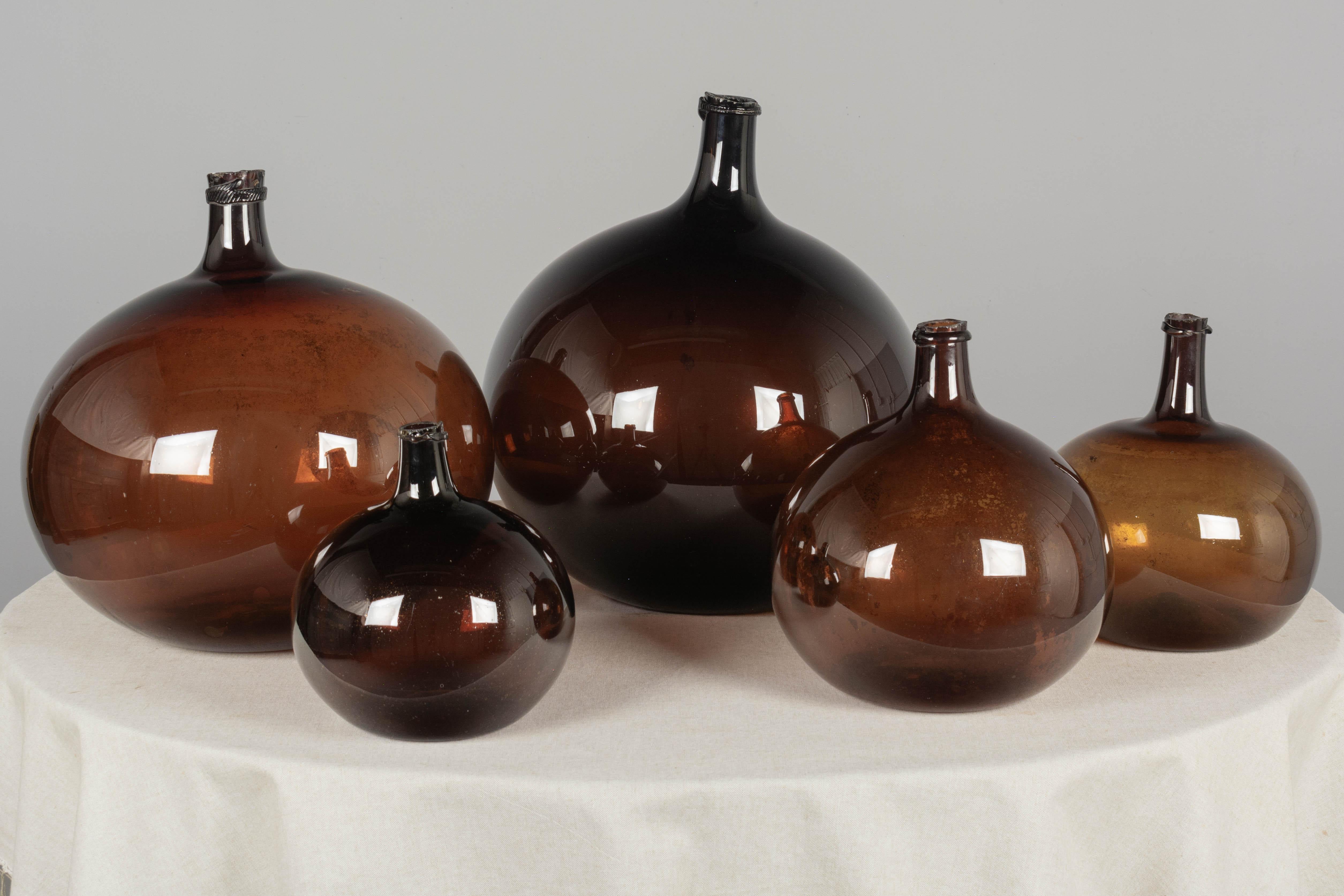 A set of five 19th century French globular form amber glass demijohn bottles with air bubbles typical of handblown glass. Circa 1850-1860
Dimensions (left to right): 
18