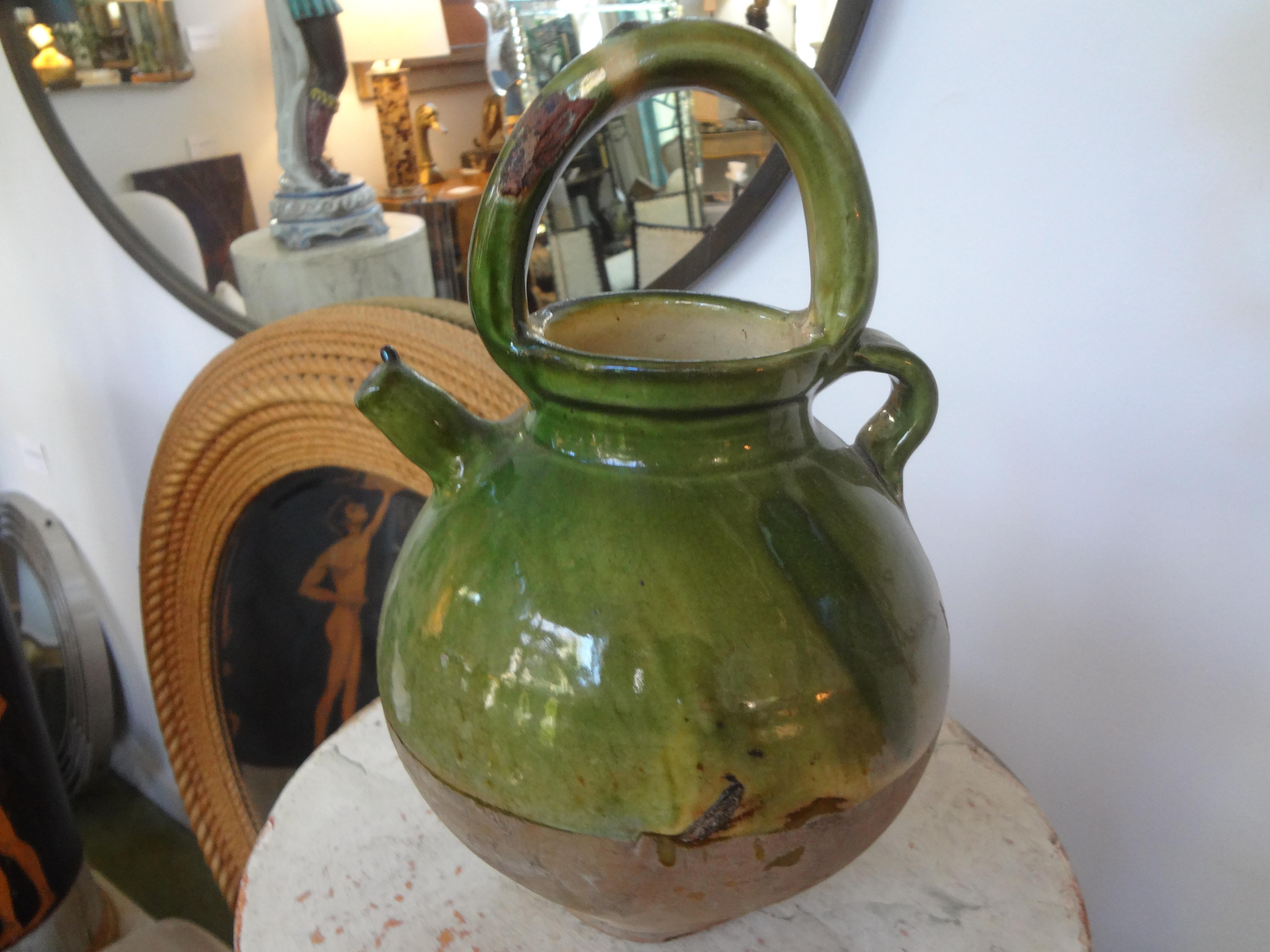 A 19th century French green glazed terracotta pottery vessel or pitcher. This vessel was used for milk or as a vinegar pot (vinaigrier). These vessels were most often from the Southwest part of France. Our pot is in good condition with some losses