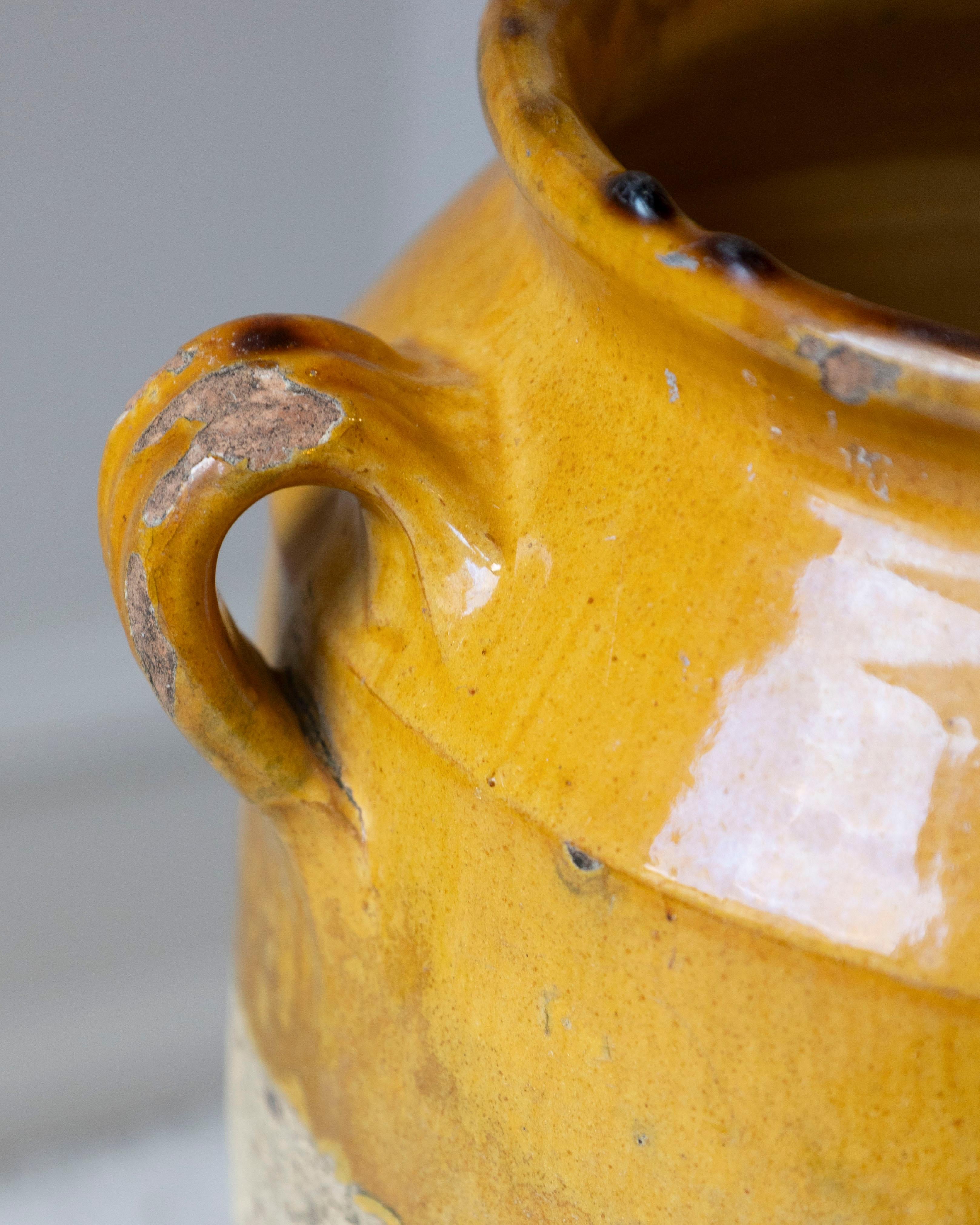 Dieser auffällige französische Terrakottakrug aus dem 19. Jahrhundert ist ein schönes Beispiel für zeitloses Dekor aus Gebrauchskeramik. Das in Südfrankreich von Hand gedrehte und gebrannte Gefäß weist im oberen Teil eine ockergelbe Glasur auf, eine