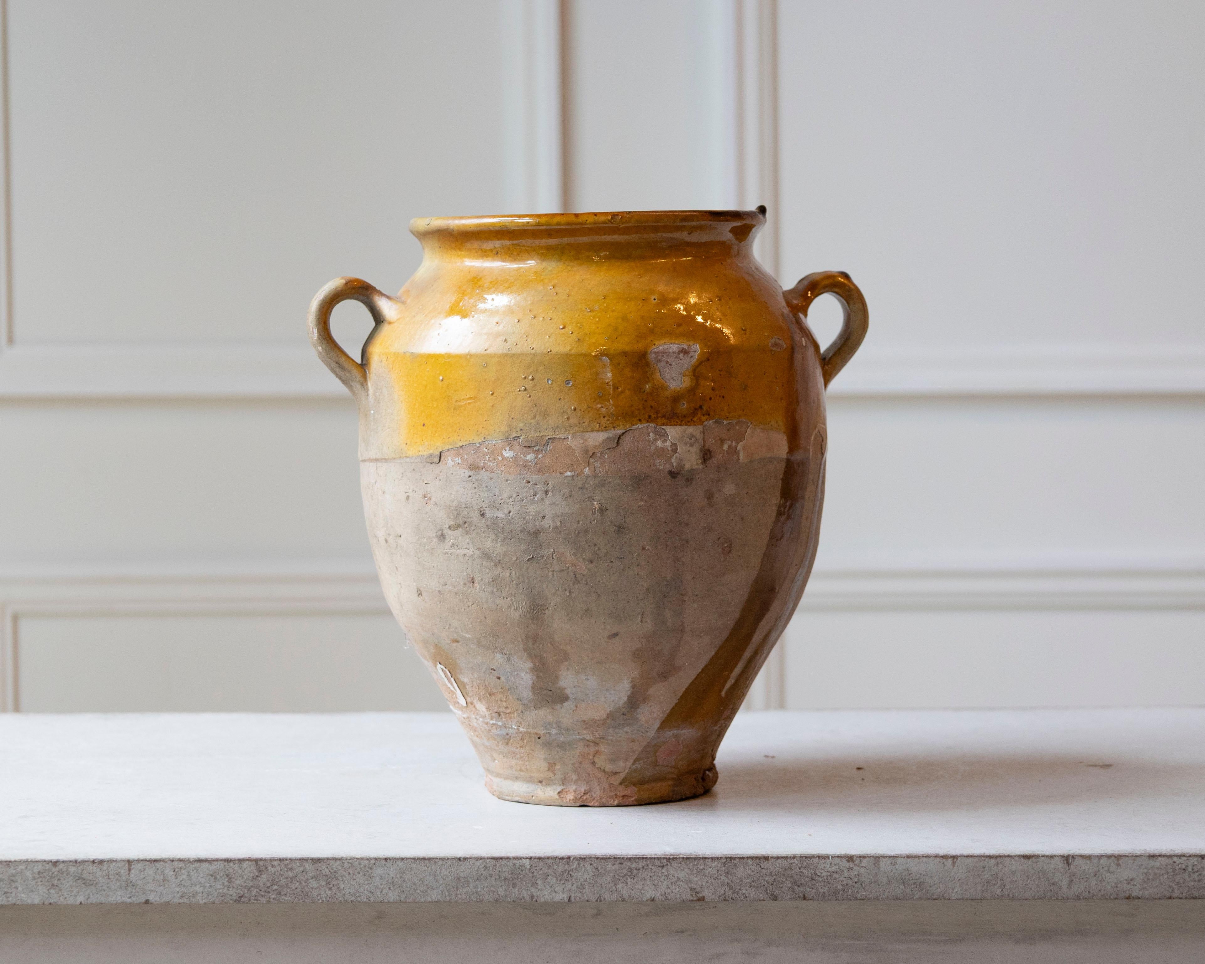 Cette étonnante cruche en terre cuite française du XIXe siècle est un bel exemple de poterie utilitaire transformée en décor intemporel. Façonné et cuit à la main dans le sud de la France, le récipient est recouvert d'une glaçure jaune ocre profond