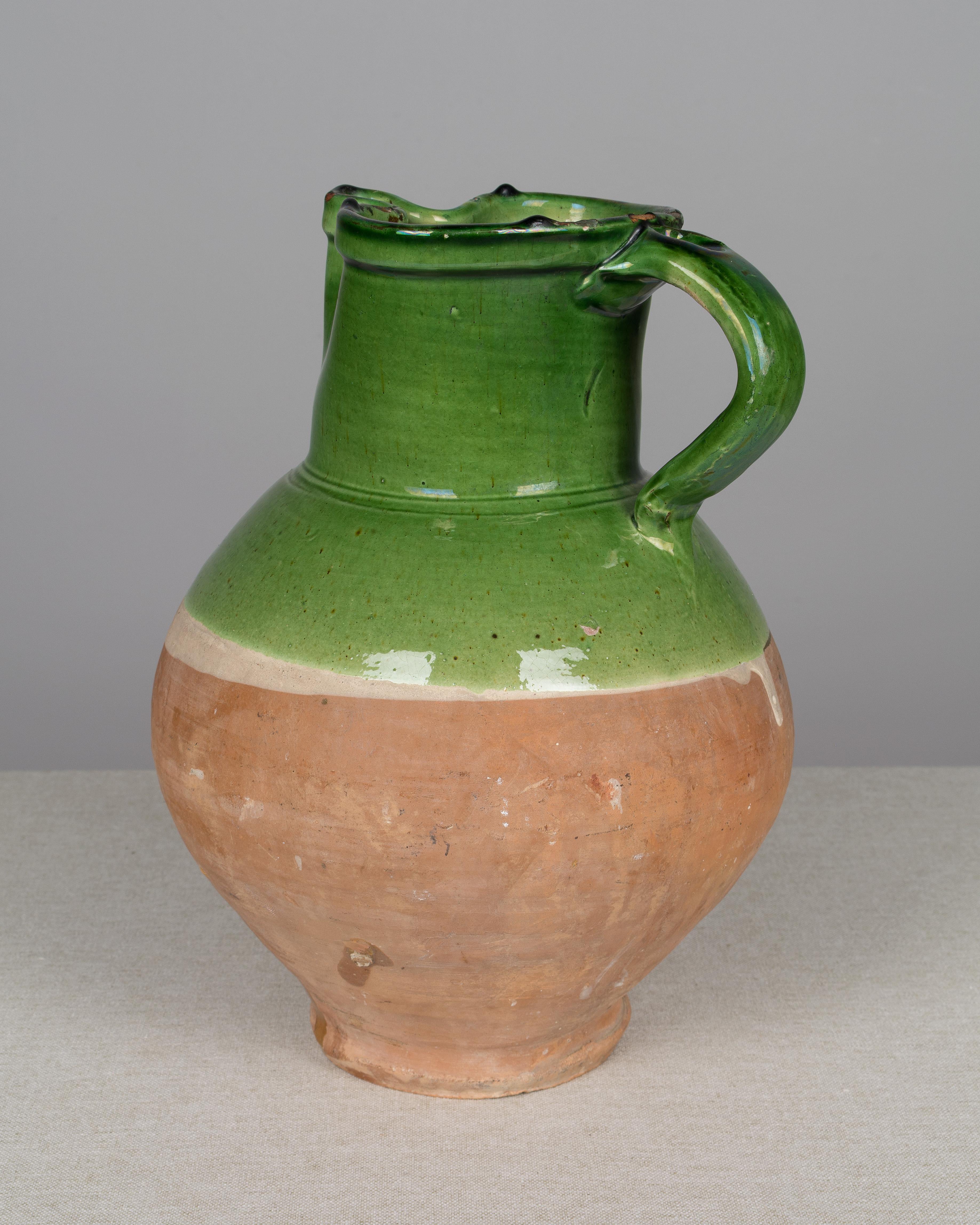 A 19th century French green glazed terracotta water pitcher. In good condition with no cracks, but there are several chips to the glaze around the rim.