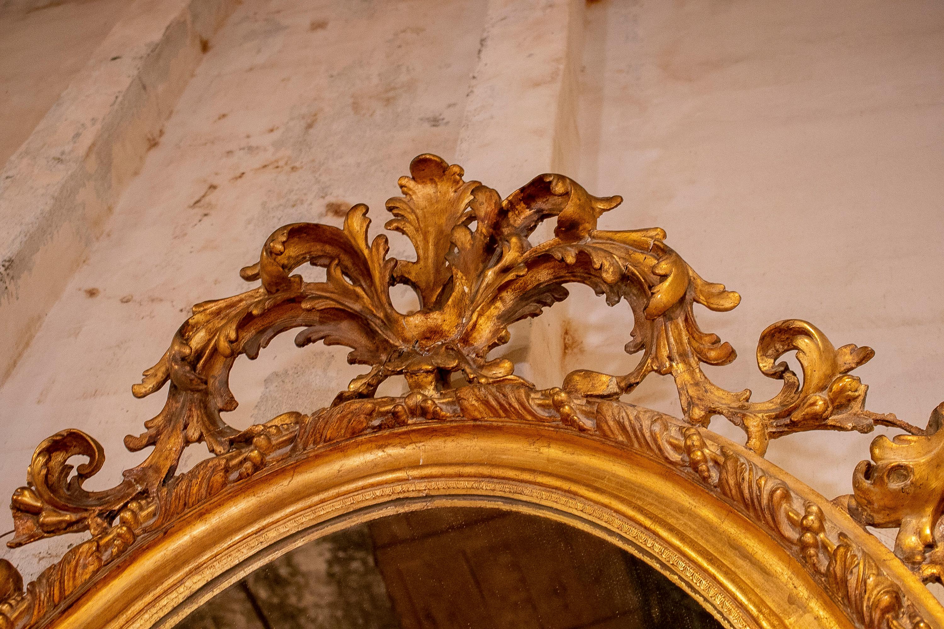 Espejo ovalado francés del siglo XIX de madera dorada con cresta y rocalla barroca en Bueno estado para la venta en Marbella, ES