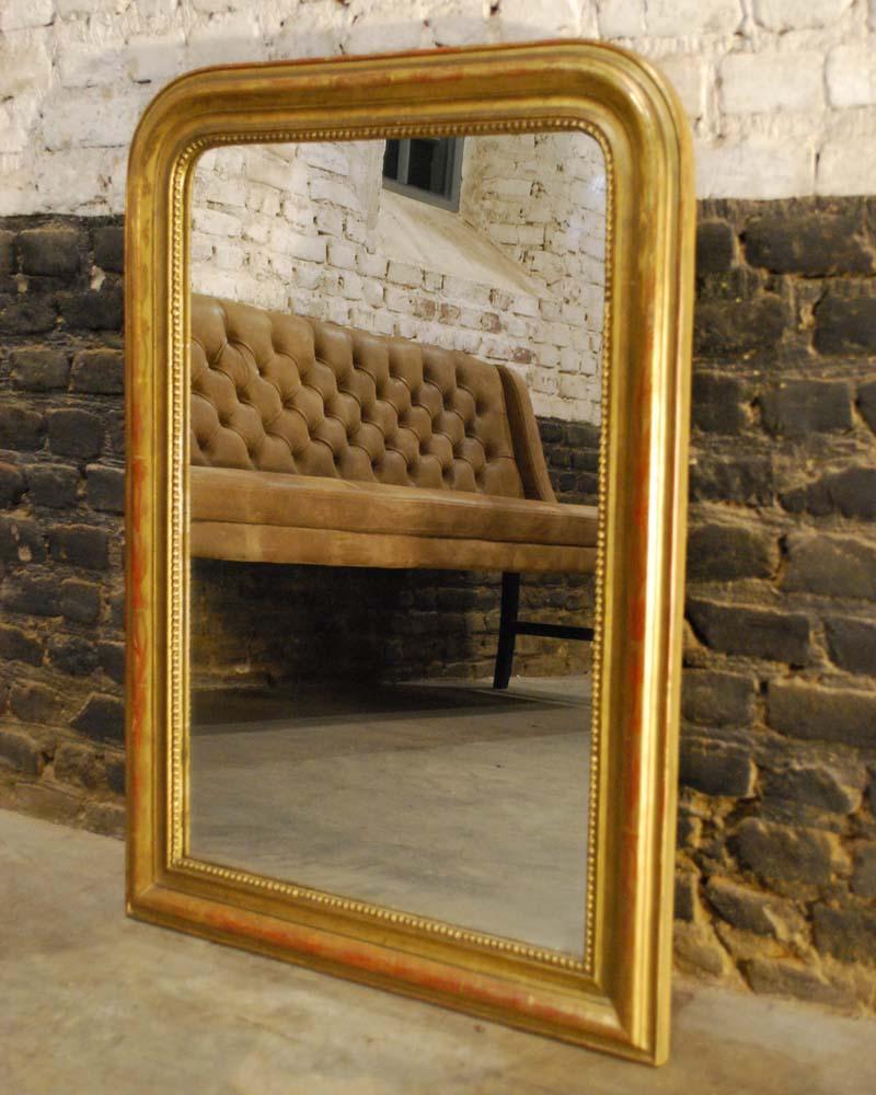 Dieser schöne kleine antike französische Spiegel ist komplett vergoldet und im Louis-Philippe-Stil mit den typischen abgerundeten oberen Ecken gefertigt. Der Spiegelrahmen ist mit einer Perlenkette versehen:: die das Glas umgibt. Der am höchsten