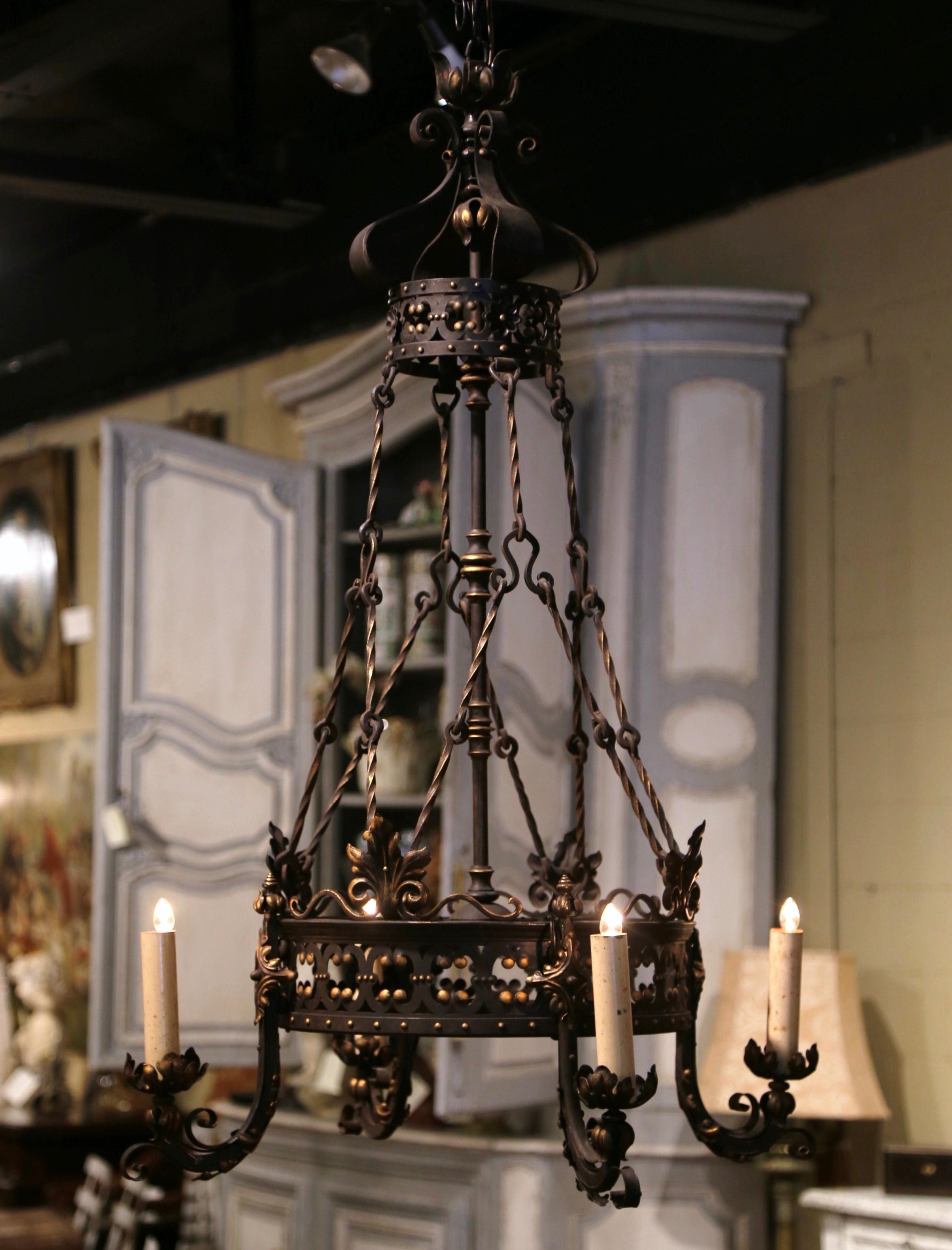 This intricate antique iron light fixture was forged in France circa 1870. Round in shape, the Gothic chandelier features a circular crown decorated with acanthus leaf and rose flower motifs in high relief around the perimeter. The tall chandelier