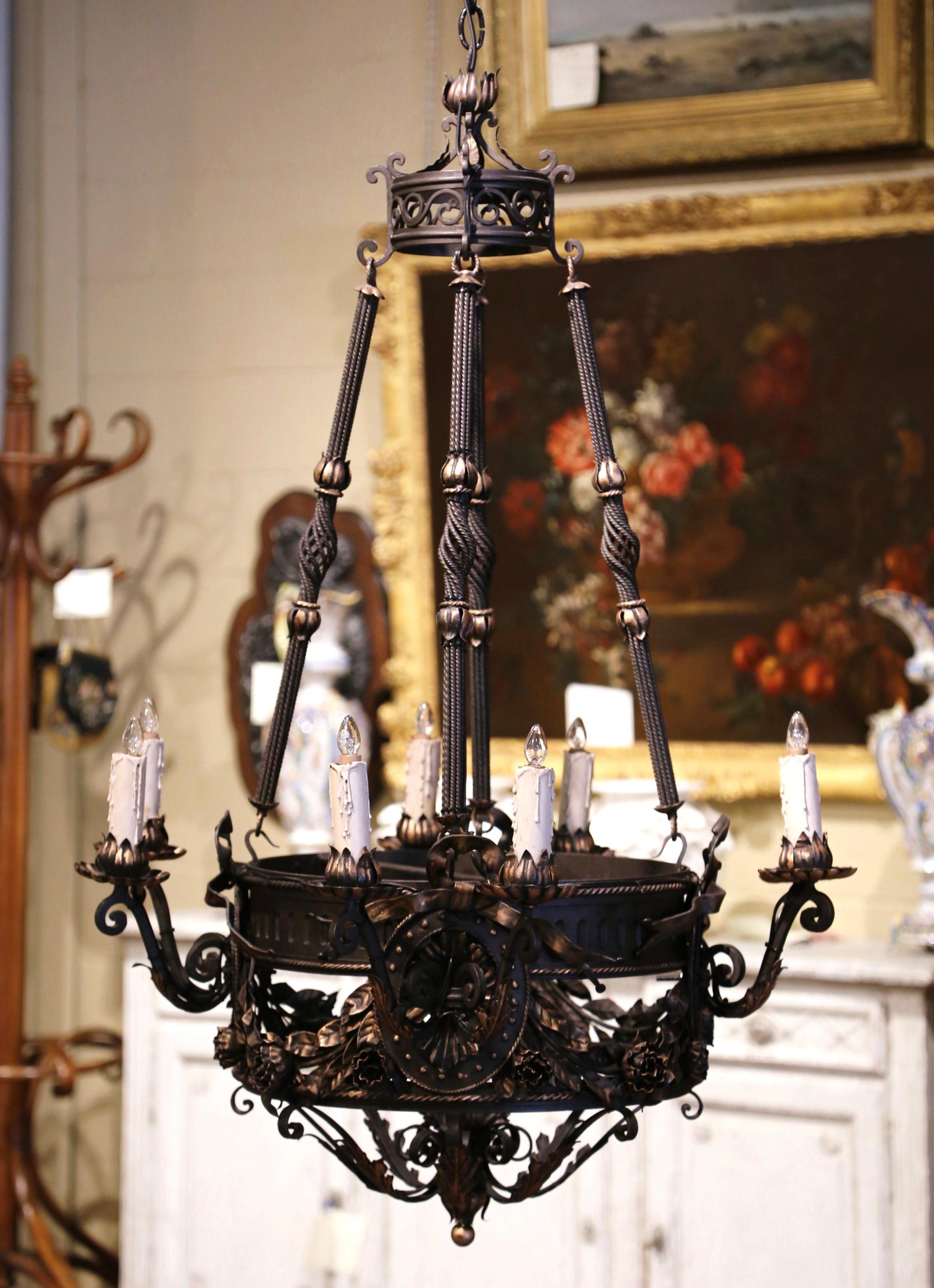 This intricate iron light fixture was forged in France circa 1870. Round in shape, the Gothic chandelier features a circular crown with oval medallions decorated with acanthus leaf and rose flower motifs in high relief, and embellished with ribbon