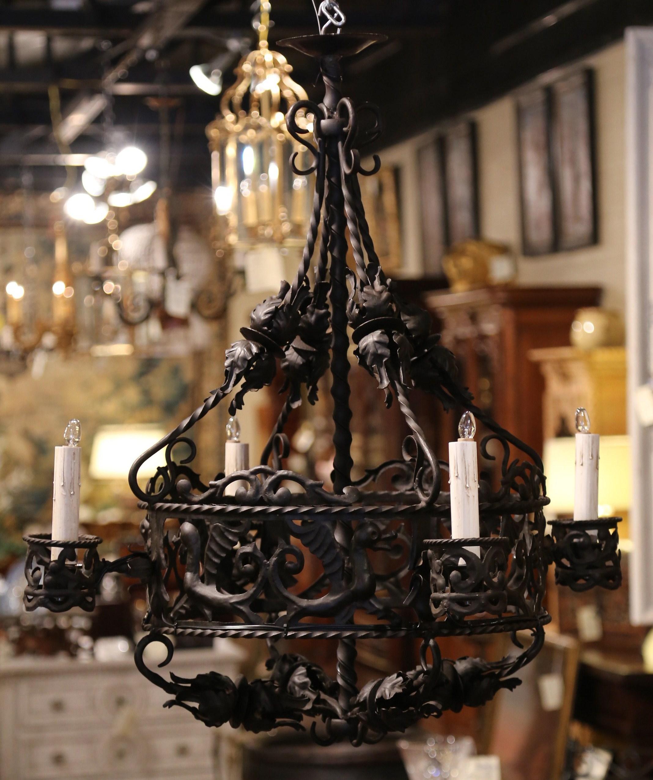 This intricate iron light fixture was crafted in France, circa 1870. Round in shape, the Gothic chandelier has a central twisted post and features a circular crown embellished by dragonfly figures and floral decor; the fixture is also decorated with