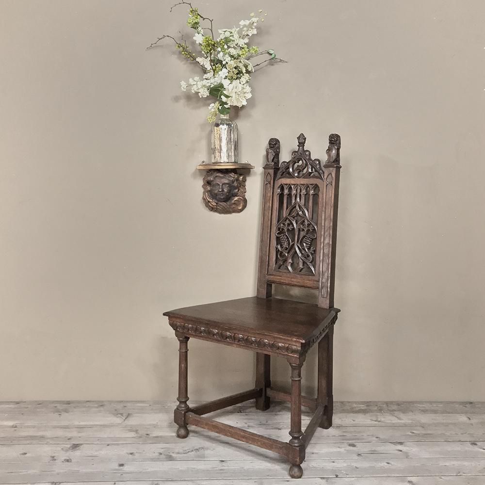 19th century French gothic chair was handcrafted from solid old-growth oak, and features a splendid execution of the Gothic style which was formalized in the mid-12th century in St. Denis, France. Grape clusters carved into the seatback represent