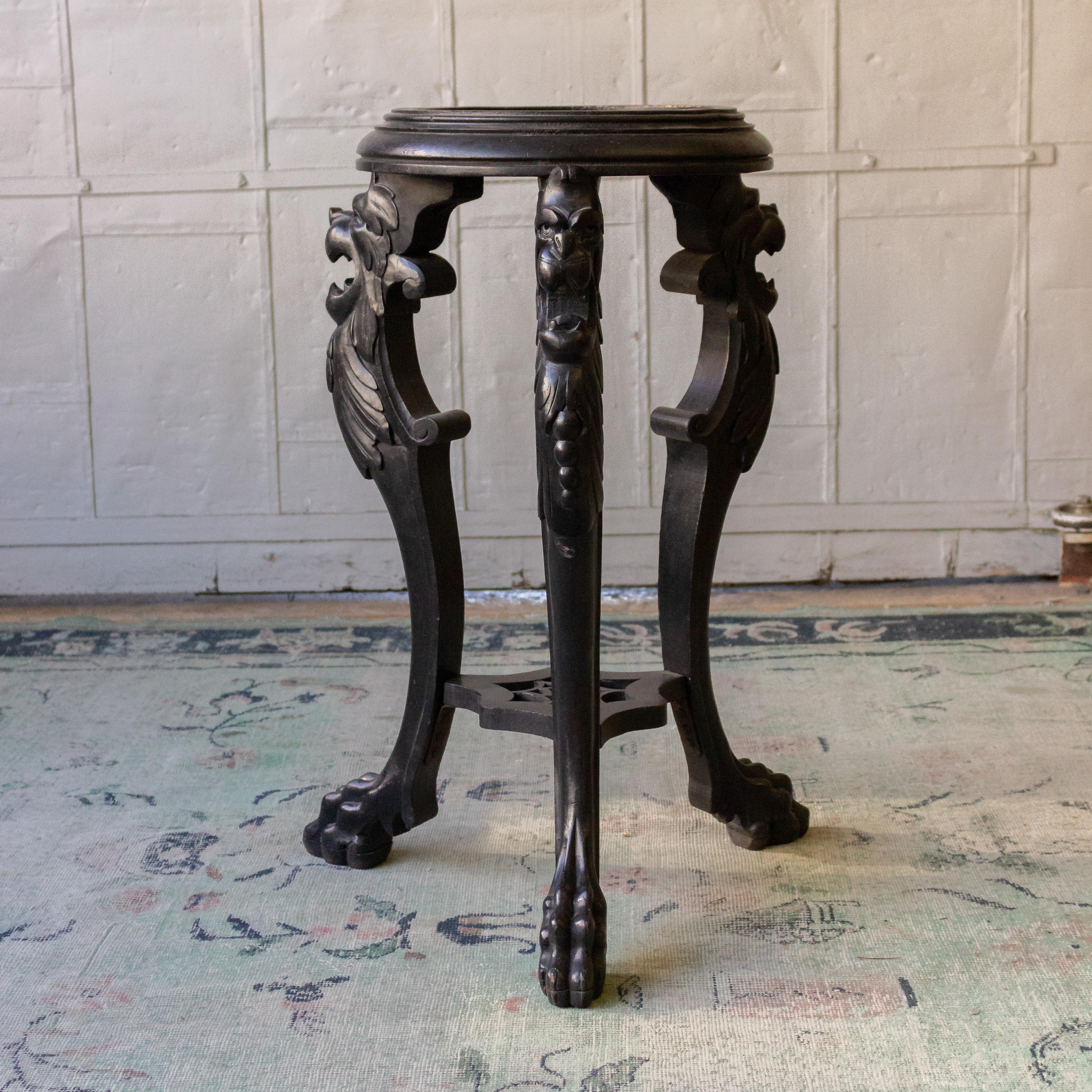 Ebonized carved wood pedestal or end table with claw feet and round top.