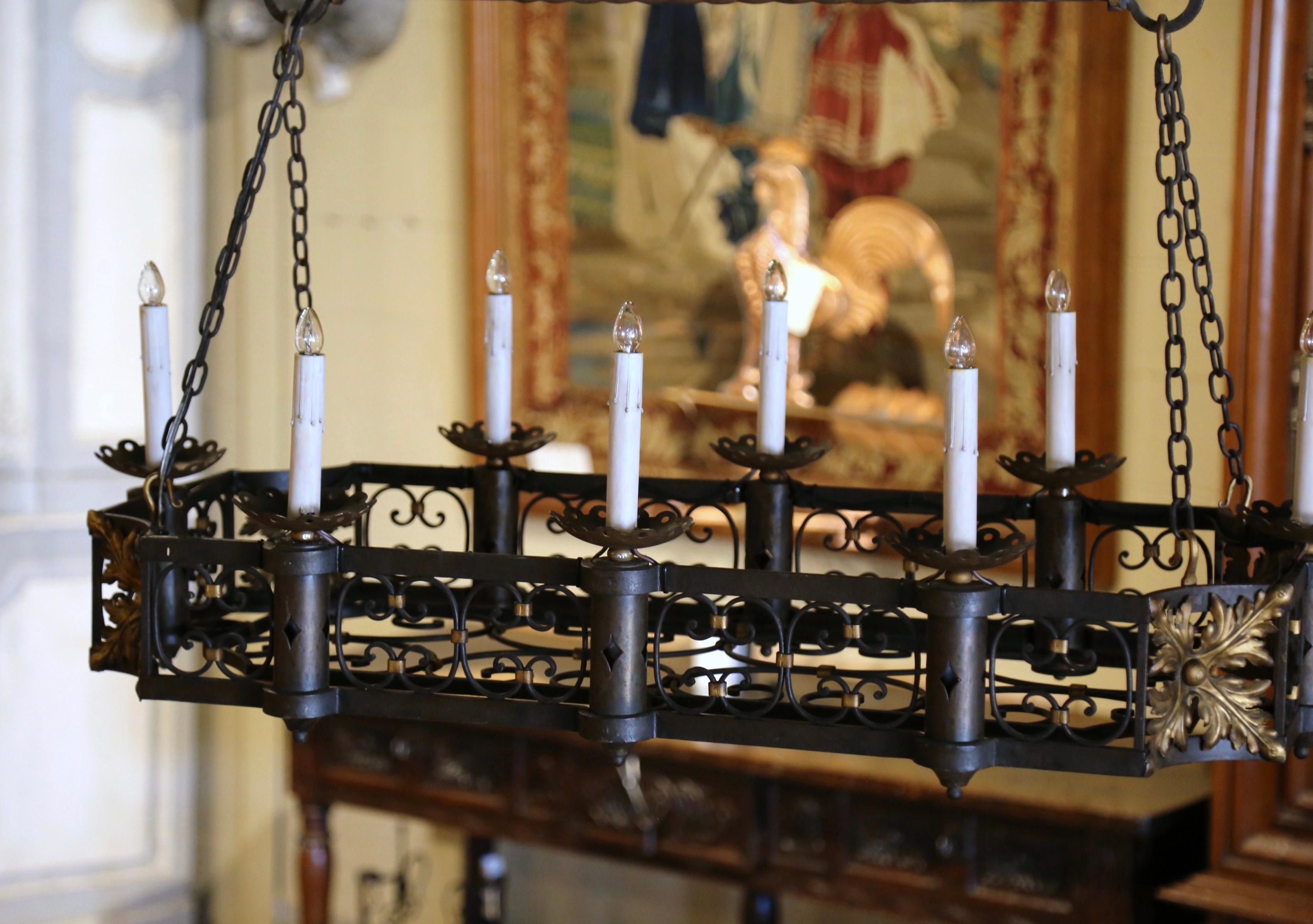 Questa elegante lampada antica è stata forgiata in Francia, intorno al 1890. Di forma rettangolare e lungo quasi un metro e mezzo, il lampadario con fondo piatto presenta un'intricata galleria traforata con volute lungo il perimetro e impreziosita