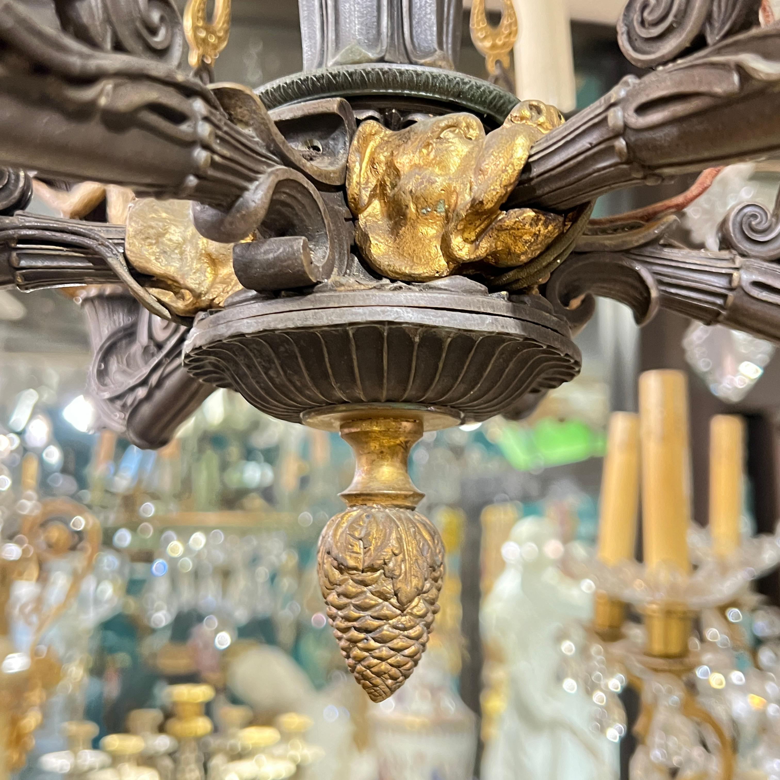 Antique (late 19th century) chandelier in the gothic style with six electrified candles and modern wiring, featuring a baluster suspended from six chains, decorated with gilt flame and other classical motifs gradrooning and scrolling foliage, and