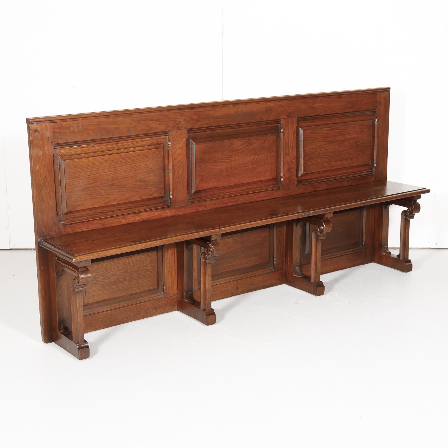 19th century antique French Gothic Revival period church pew or hall bench handcrafted near Saint Lô in Normandy from solid oak, circa 1880s. This large church pew features three raised panels on the back with three matching panels below the seat.