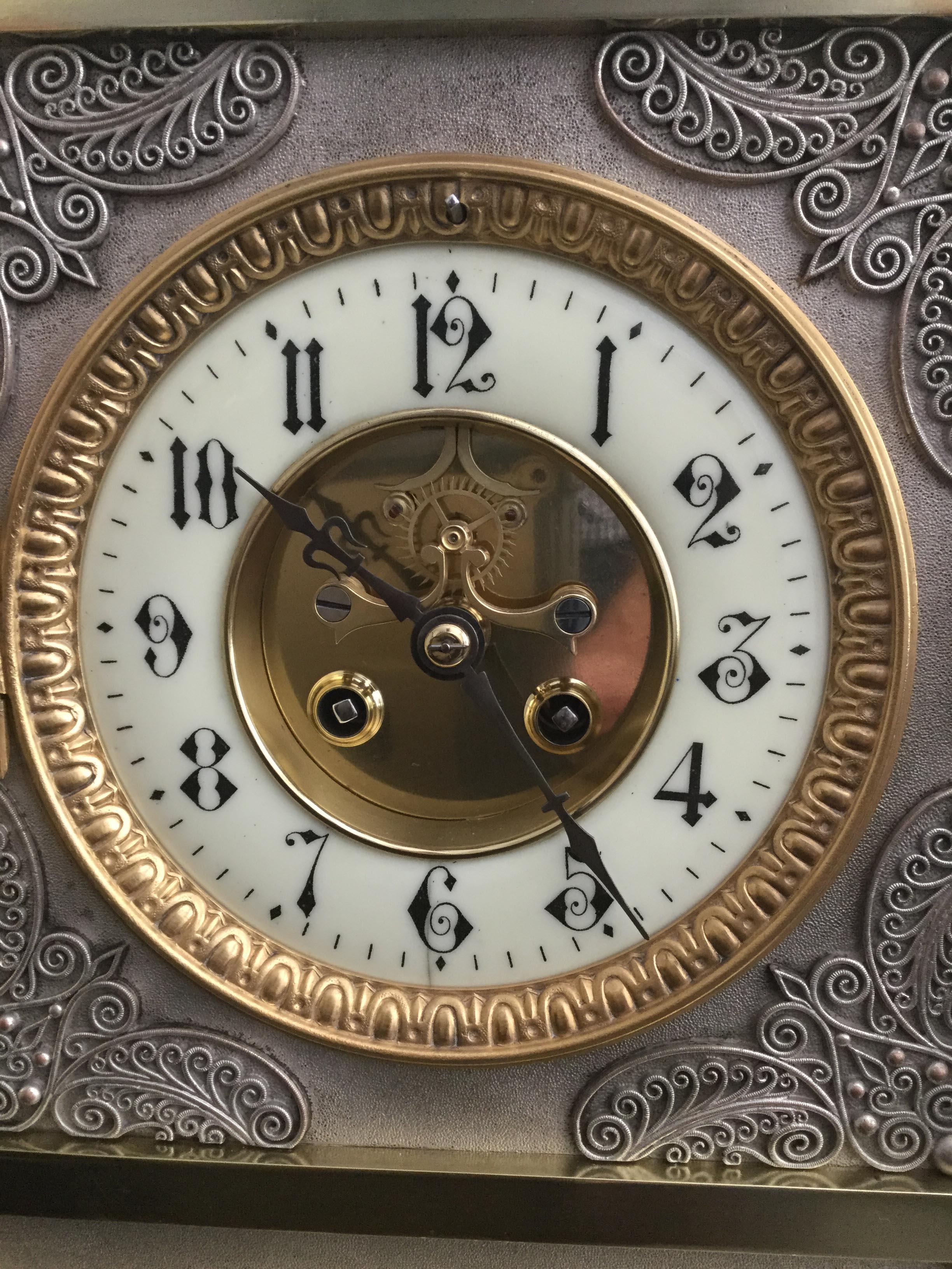 A rare French Gothic style mantel clock with brass case inset with decorative silvered panels profusely decorated in relief, surmounted to the corners by four brass and silvered orbs and a central frieze of 23 brass finials. Mounted on silvered ball