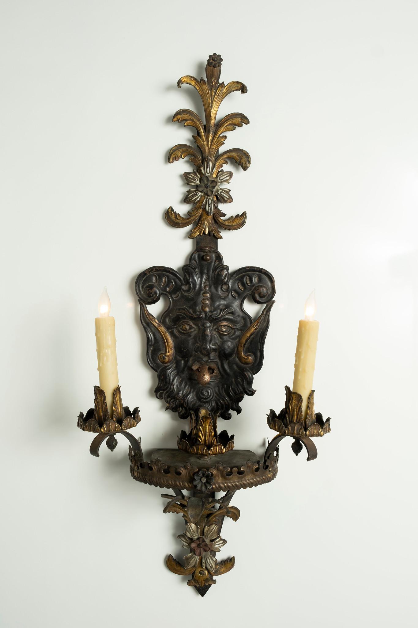 A tall pair of 19th century French Gothic iron sconces. Wonderfully detailed features include patinated gargoyle faces accented with gilded acanthus.