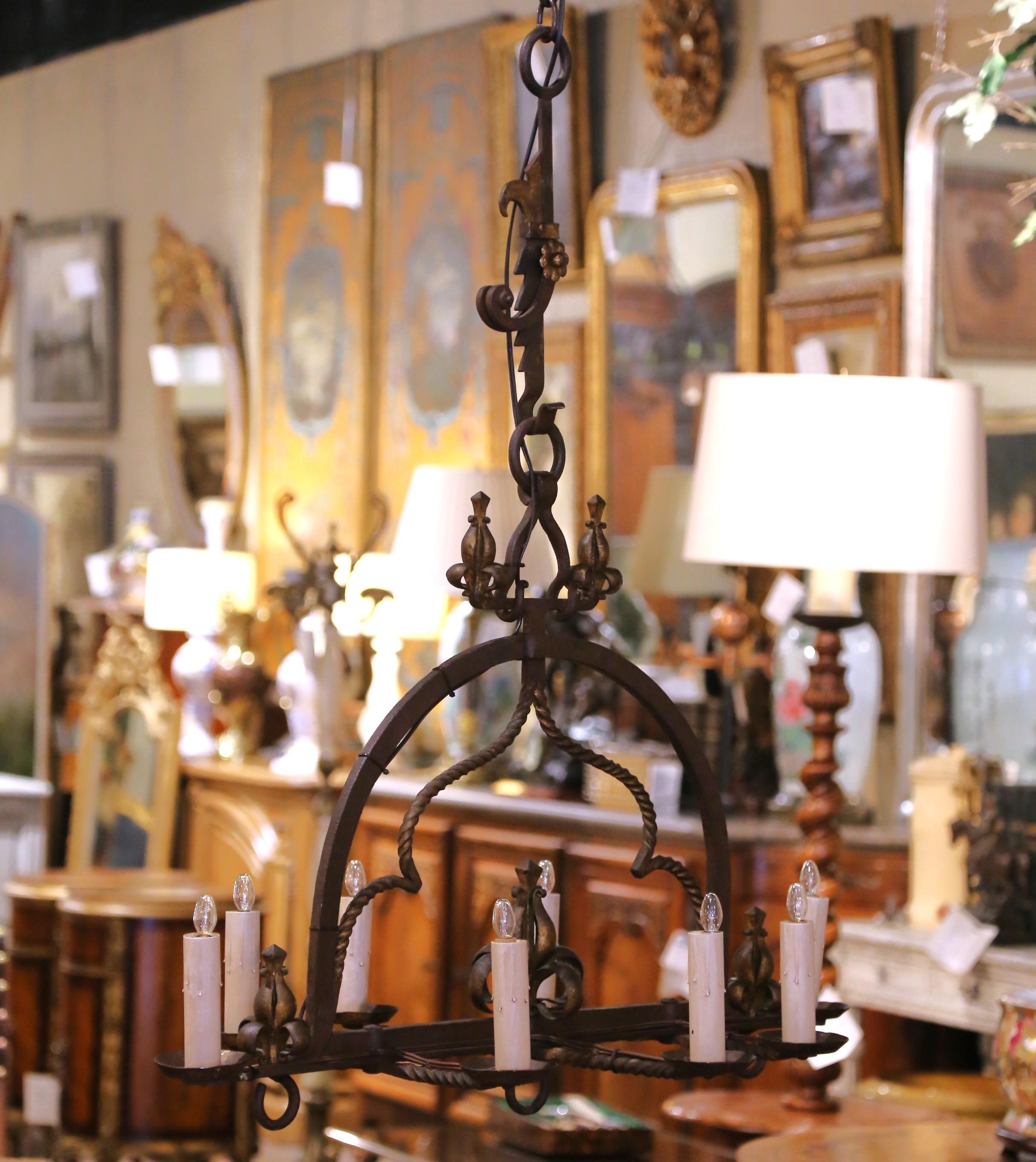 This impressive antique chandelier was crafted in France circa 1880. Forged from heavy wrought iron, the eight-light fixture showcases bold Gothic design with scrolled arms, twisted supports, and decorative Fleur-de-Lis motifs. The iron surface is