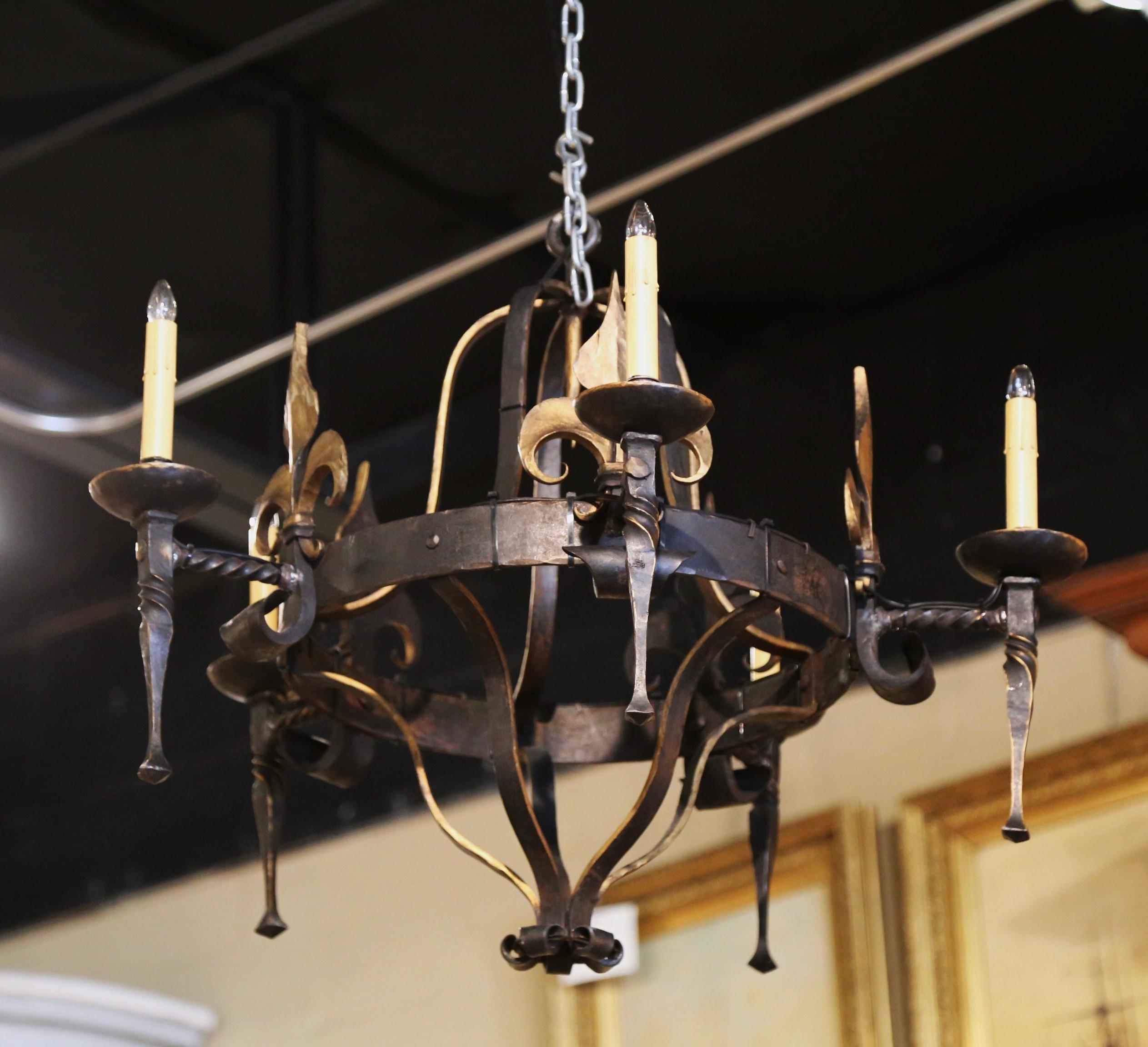 Place this large antique light fixture over a dining room, breakfast room island, or in a den. Crafted in France circa 1960, and made of wrought iron, the round chandelier is decorated with multiple Fleur-de-Lys motifs throughout. The elegant