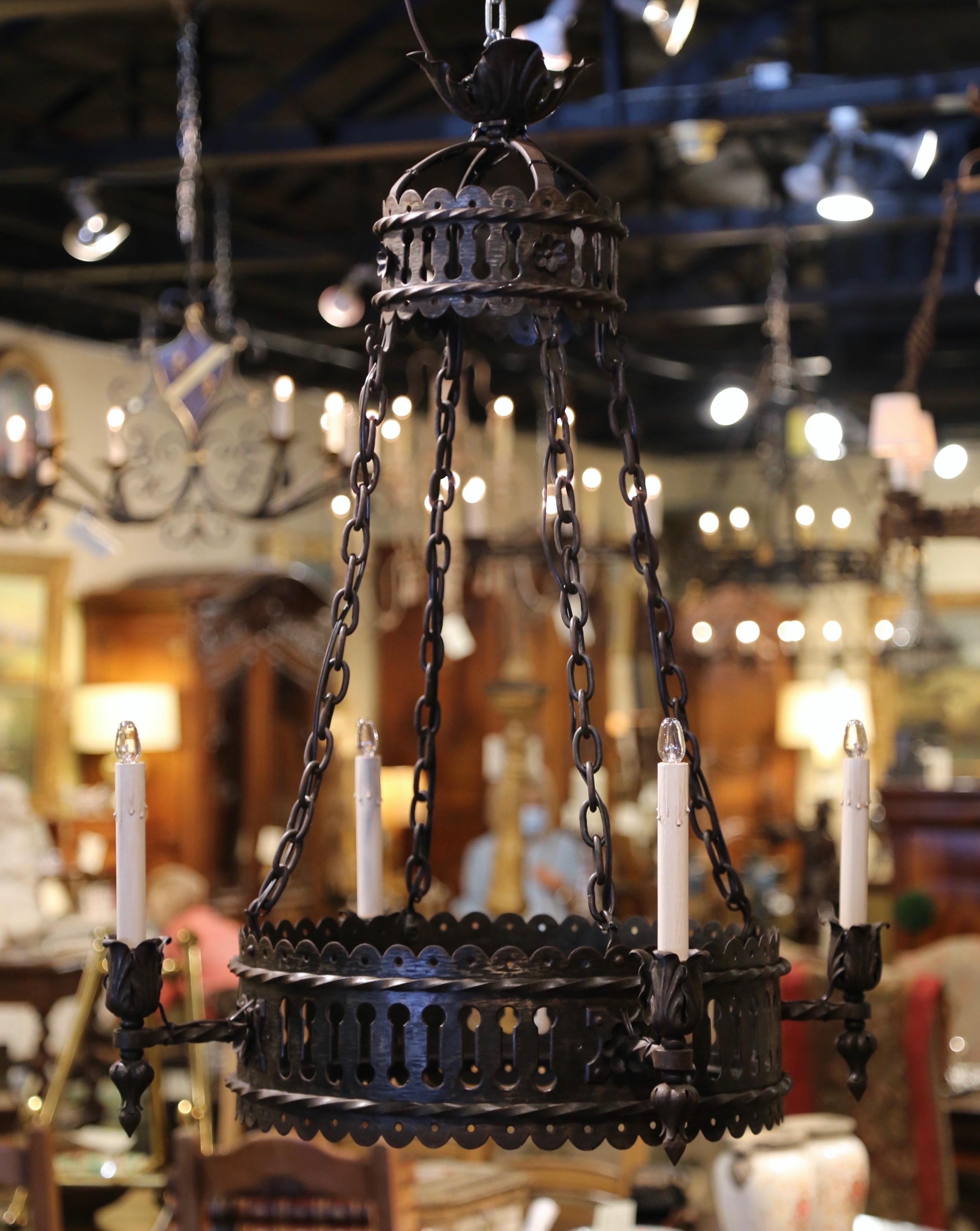 This antique Gothic light fixture was crafted in France, circa 1870. Round in shape, the wrought iron chandelier features a thick scalloped ring decorated with geometric decor, and four chains attached to an intricate and elegant top crown. The