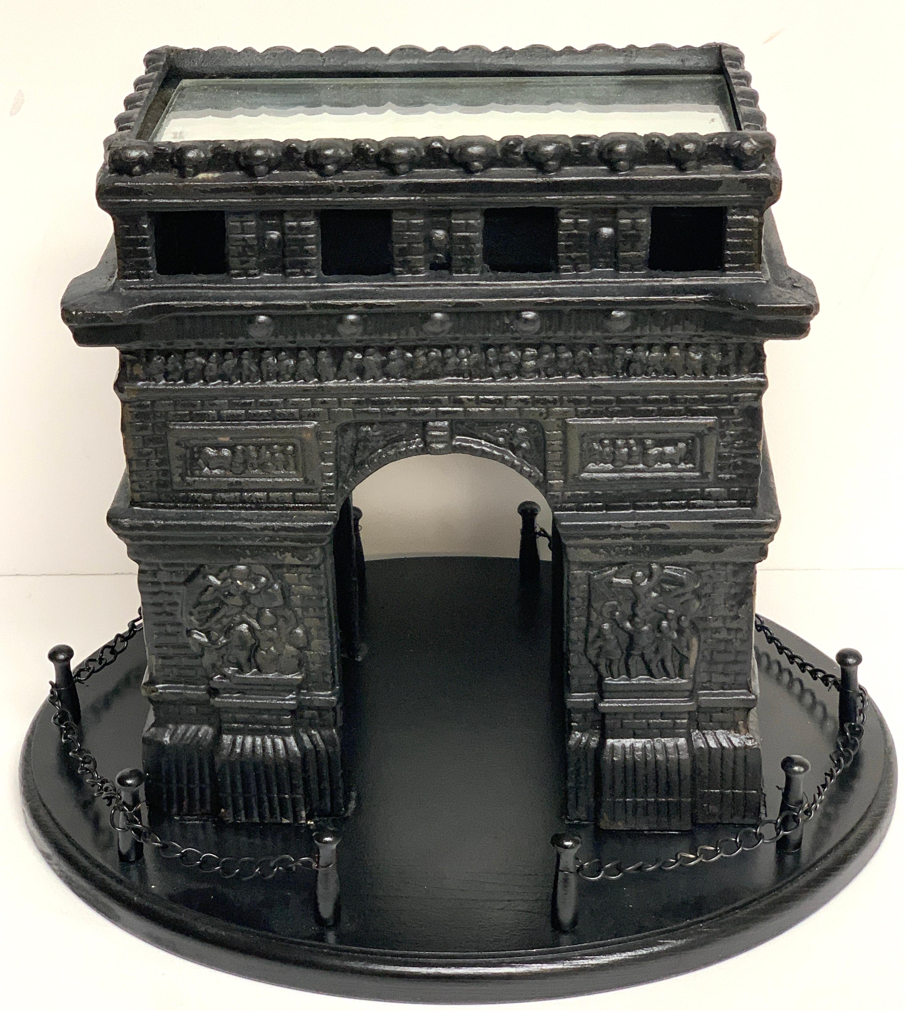 19th century French grand tour iron model of the Arc de Triomphe, in two parts, the fine cast iron model of the Arc de Triomphe with a mirrored top. Raised on a oval ebonized wood and metal chain link fenced base
Model of Arc de Triomphe measures: